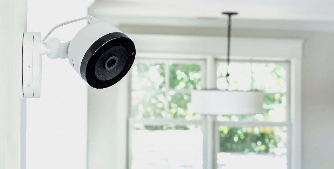 An indoor security camera mounted on a white wall in a modern home.