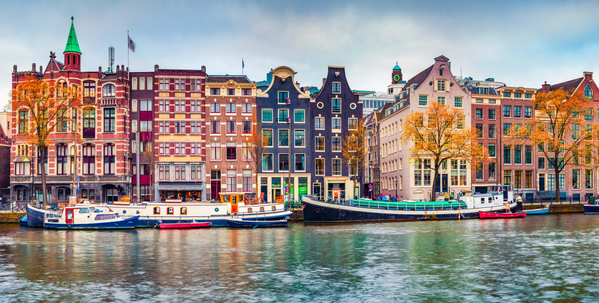 Panoramic autumn view of Amsterdam's colorful row houses along a canal.