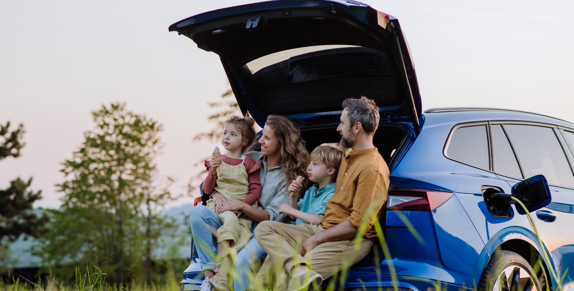 A family sits in the hatchback of their blue electric SUV