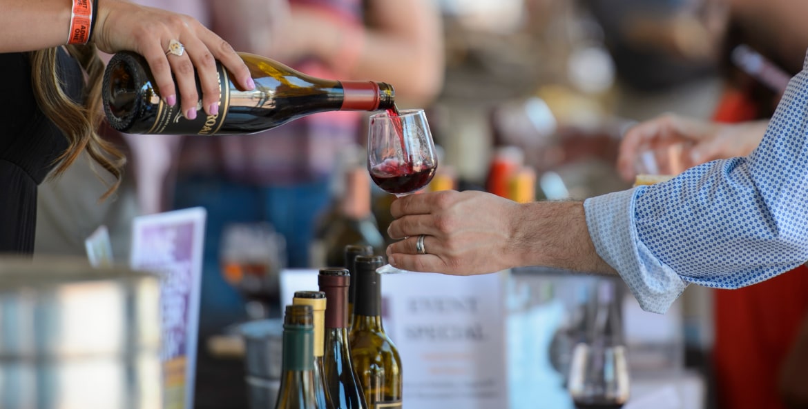 A vendor pours a glass of wine for a visitor at the Monterey Wine Festival in California.