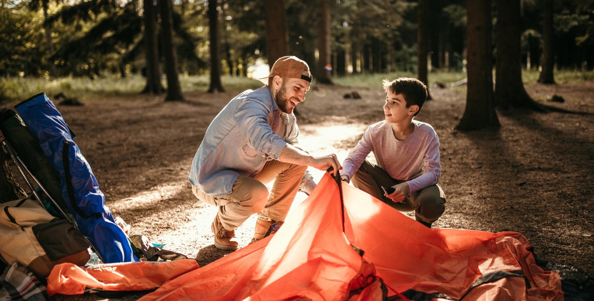 A father and son put together their camping tent.