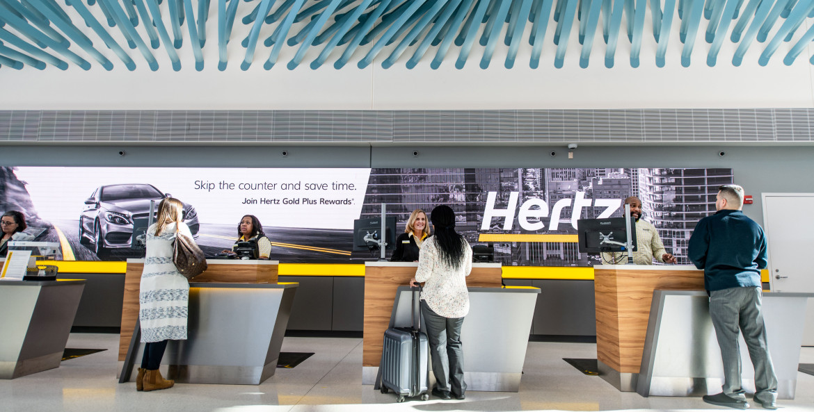 Customers pick up their rental cars from the Hertz customer service counter.
