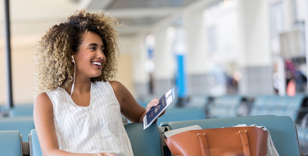 A woman talks on the phone at the airport gate while waiting for her flight.