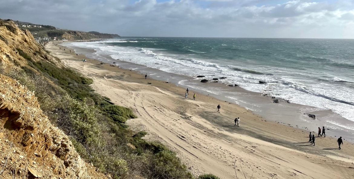 People walk along the breach at Crystal Cove State Park in Newport Beach, California.