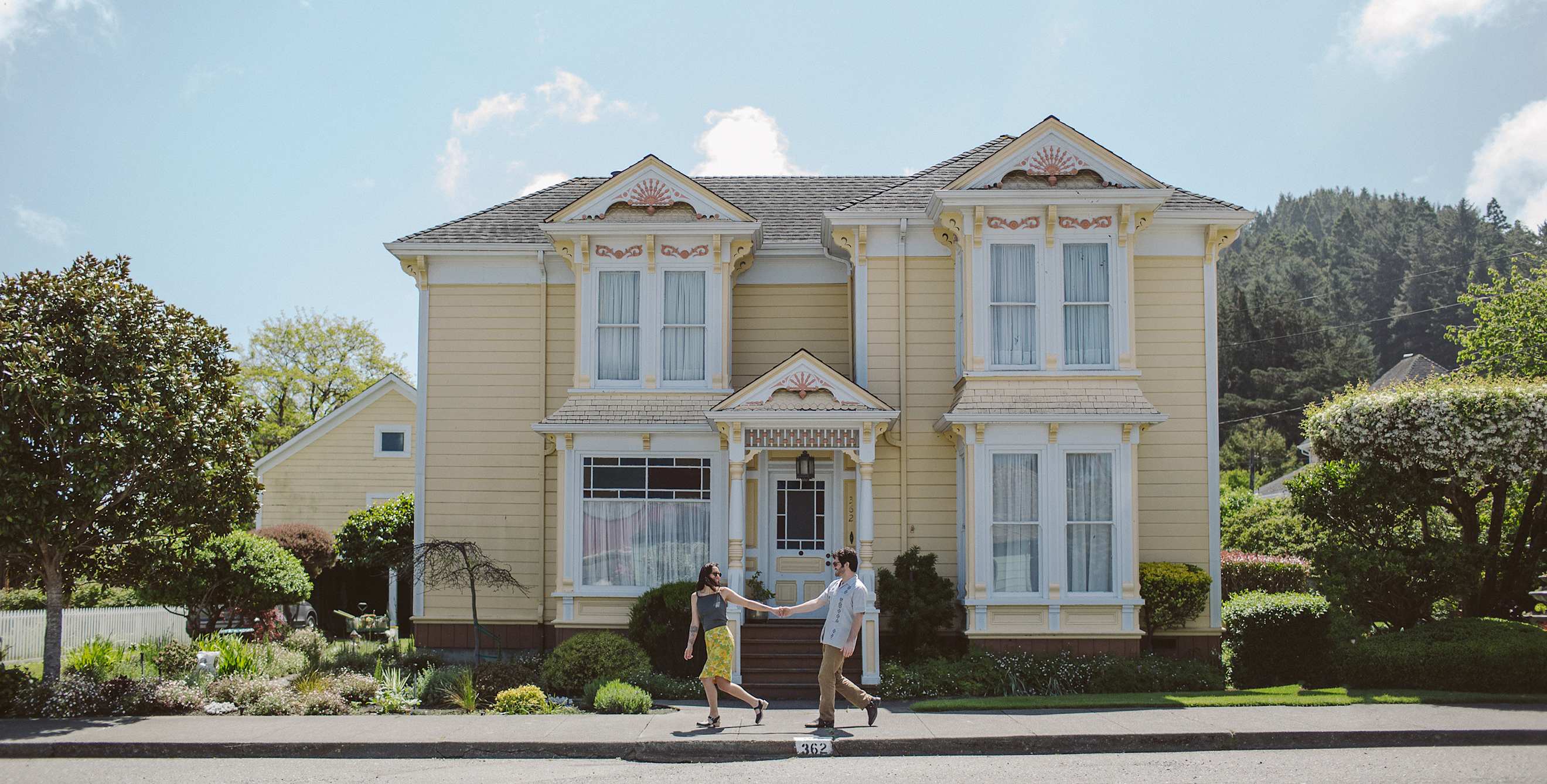 A couple walk in front of a Victorian home in Ferndale, California on the Northern California coast
