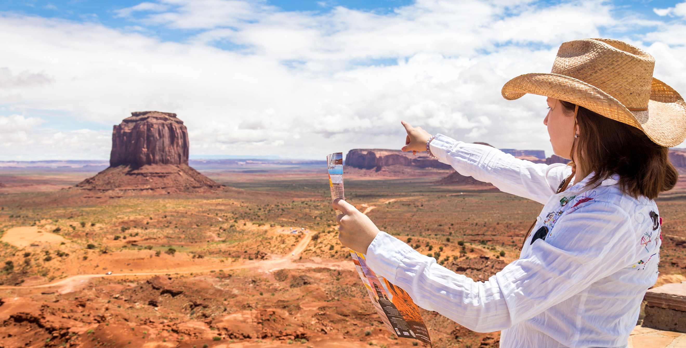 Woman in straw hat points to Monument Valley in Utah
