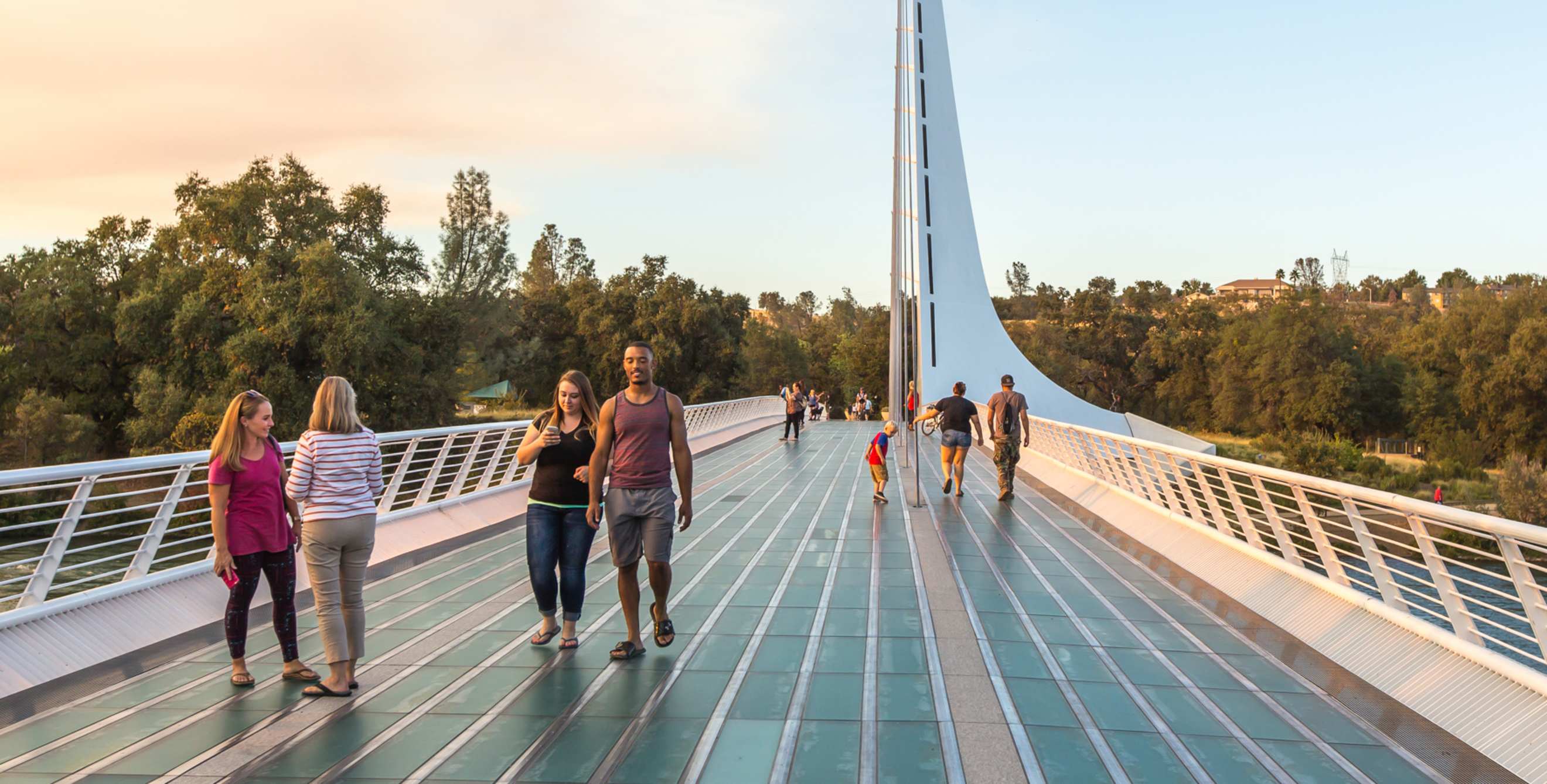 People stroll across the Sundial Bridge at sunset in Redding, California, picture