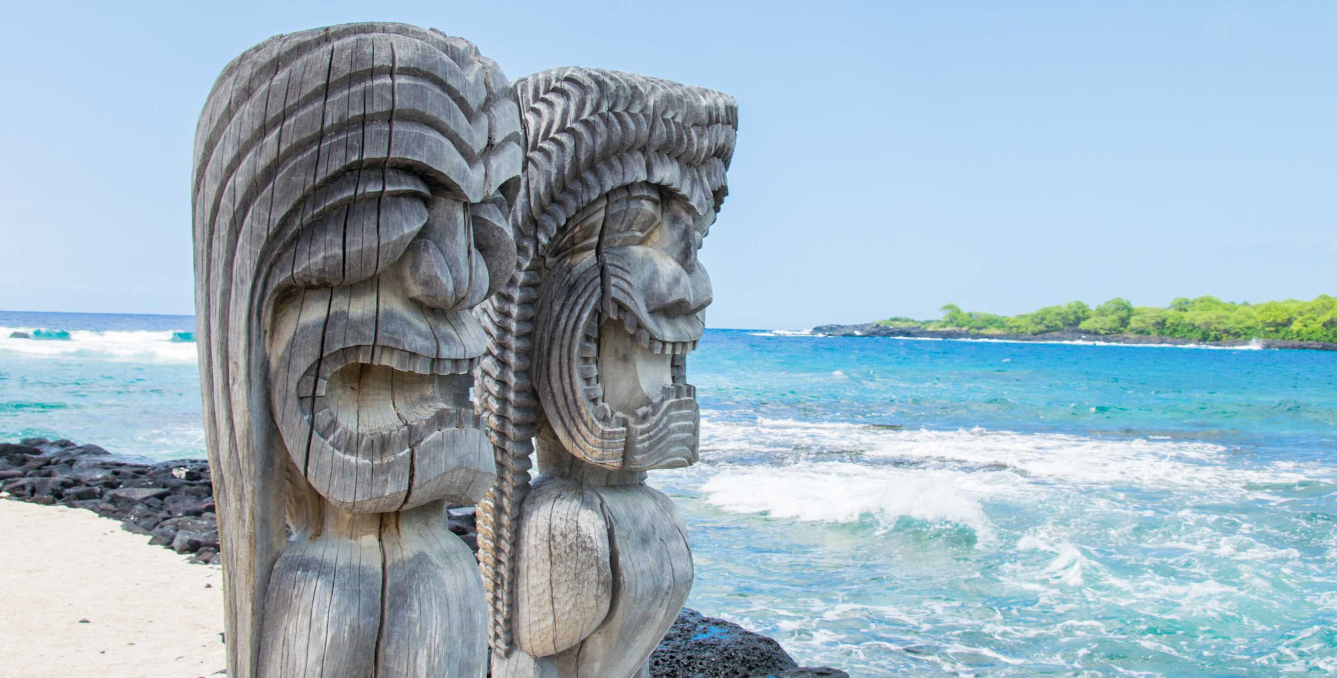 pair of carved wooden statues stand guard at Pu‘uhonua o Honaunau National Historical Park, Hawaii