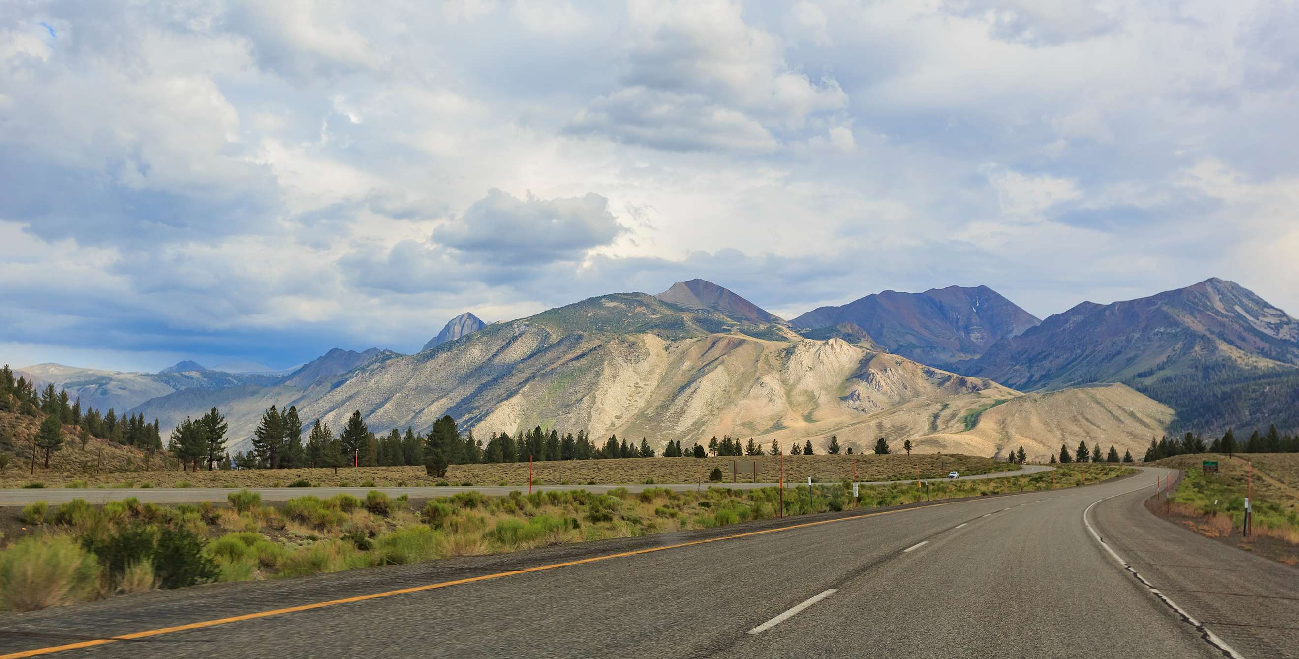 The pavement of Highway 395 in Northern California stretches towards the mountains in the distance.