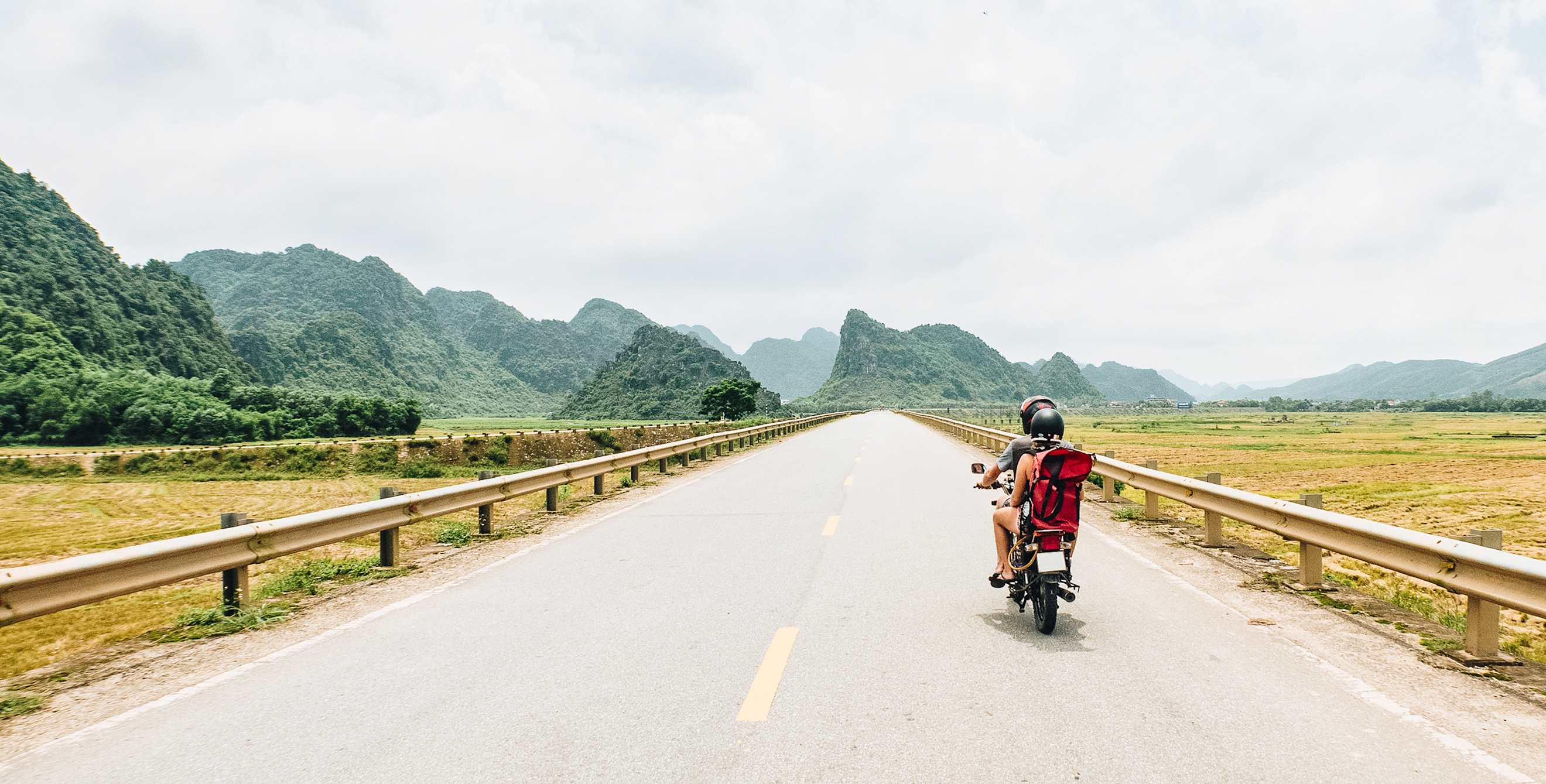 A backpacker couple rides through Vietnam on an antique motorcycle
