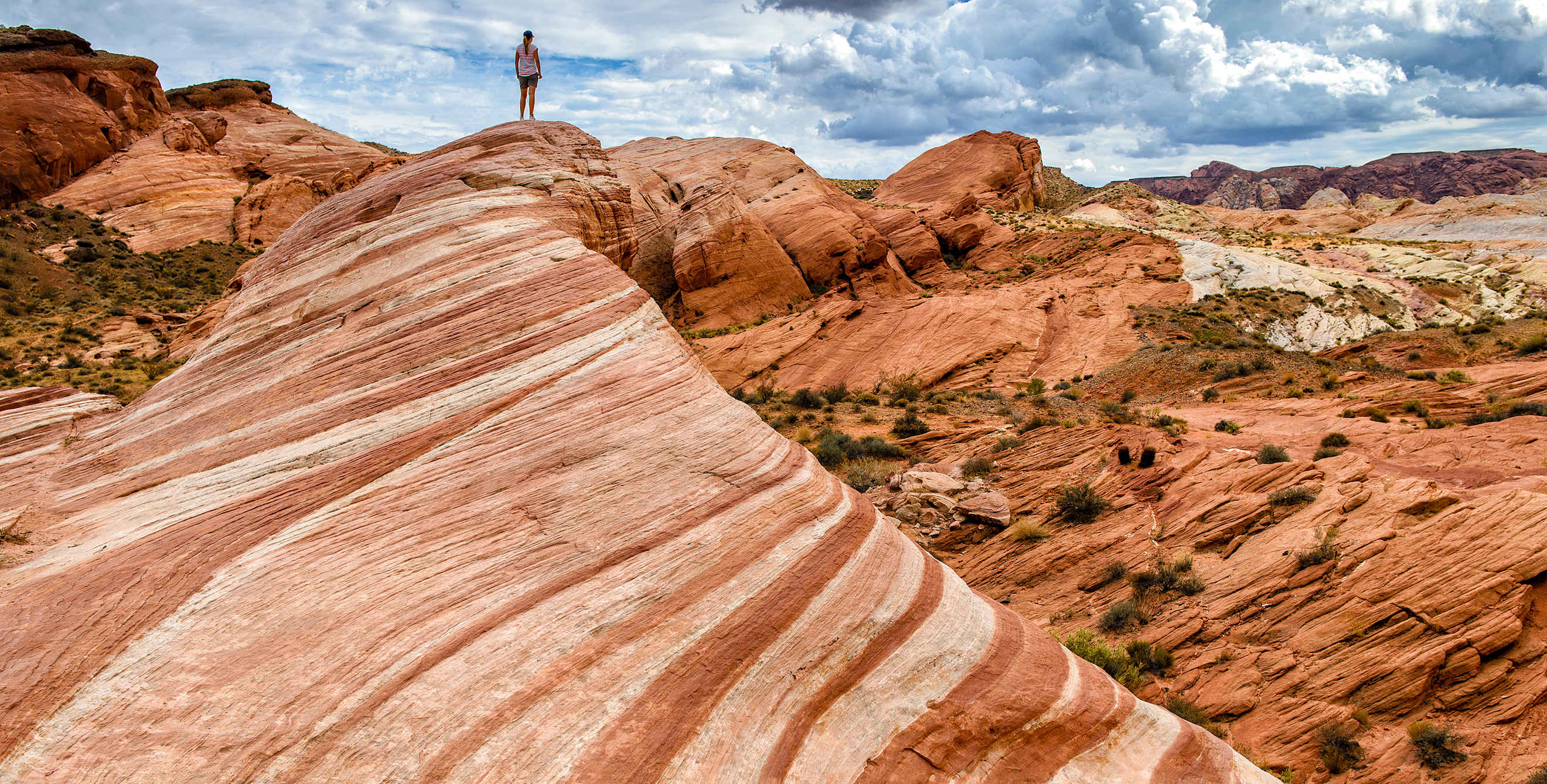 dramatic Fire Wave sandstone formation with woman standing in distance at Valley of Fire State Park in Moapa Valley, Nevada