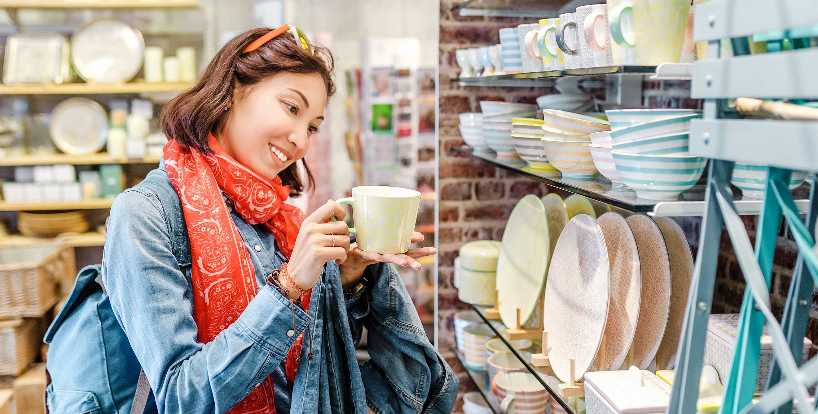Woman looks at coffee mug or tea cup in kichenware shop, picture