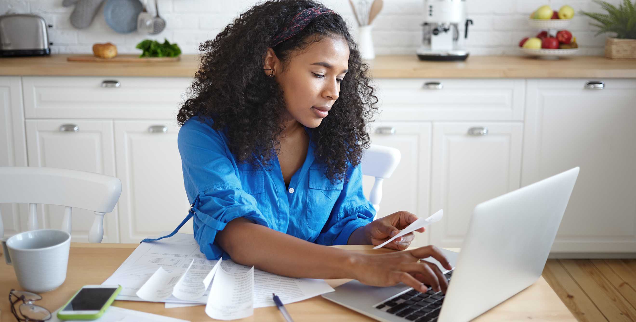 Woman calculates household budget at the kitchen table, image