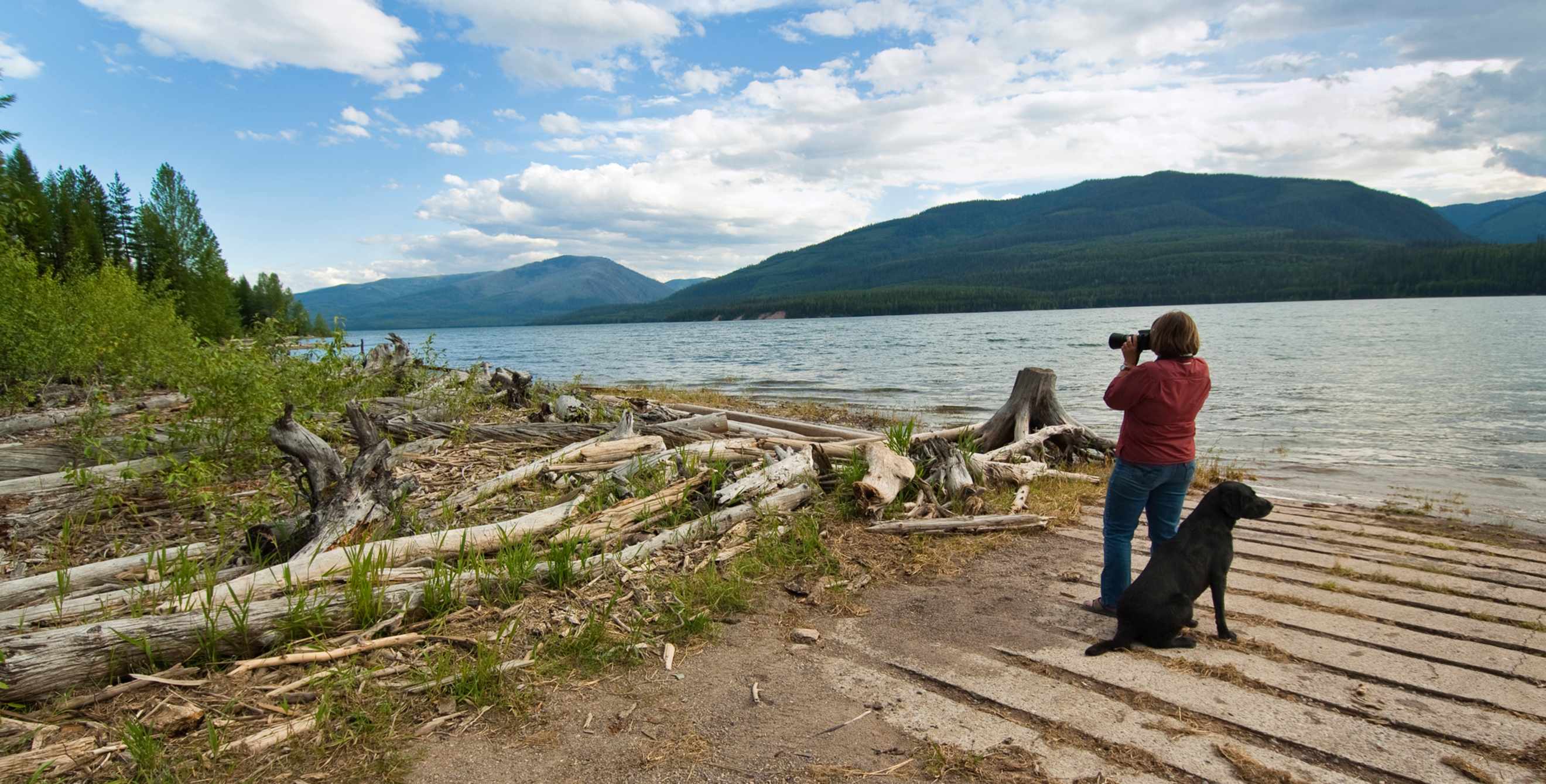 woman taking photographs with dog at Hungry Horse Reservoir in Montana