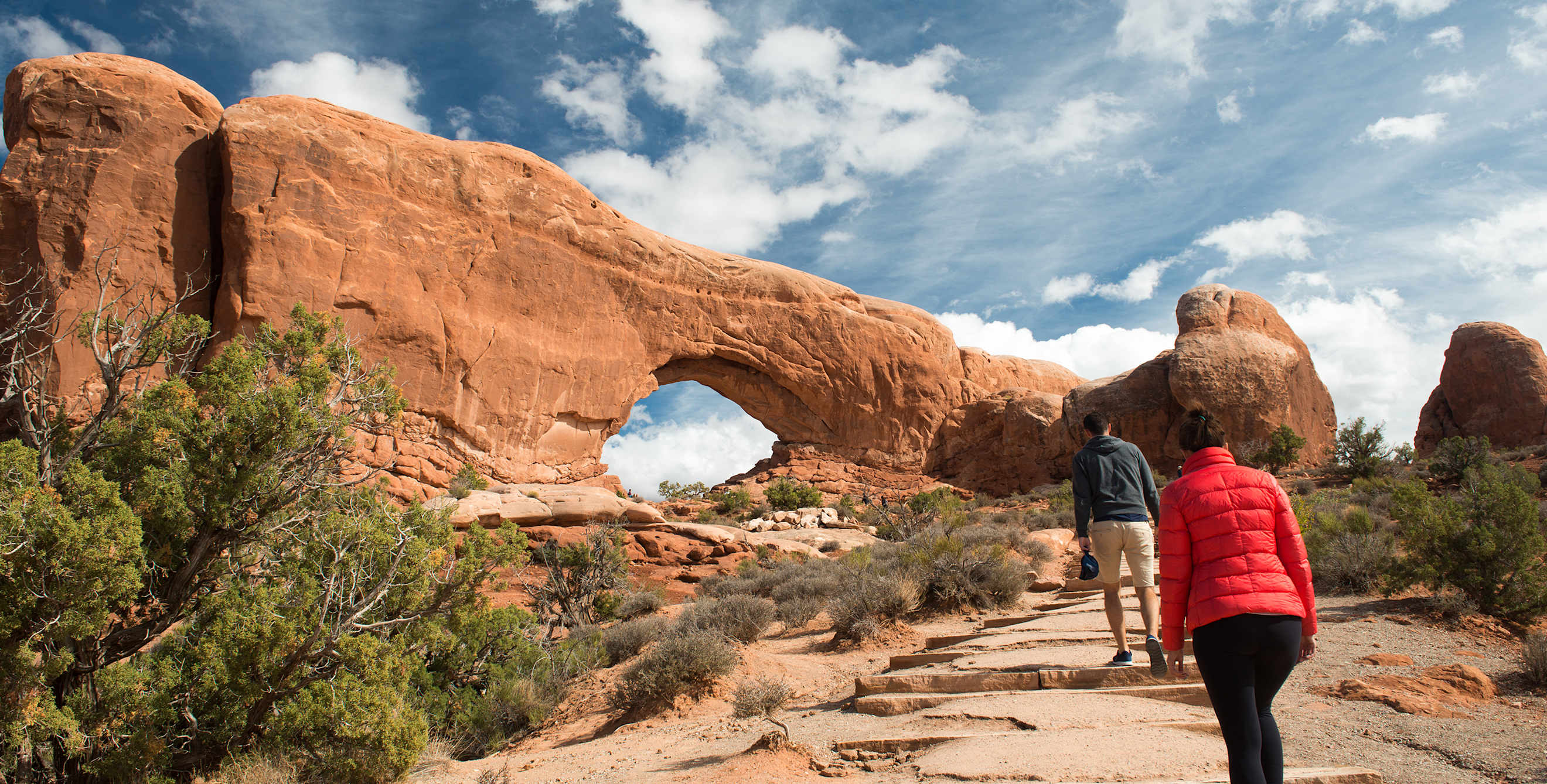 A couple hike to North Window in Arches National Park, Moab, Utah