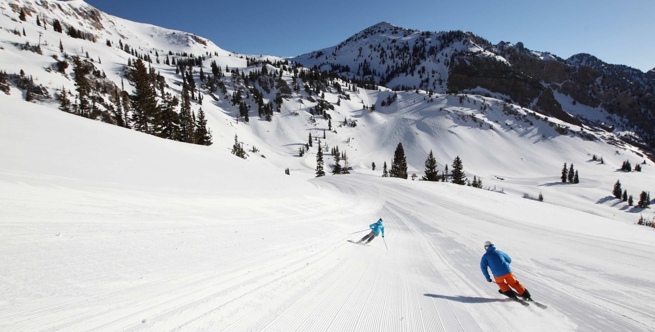 Man and woman skiing a groomed run at Snowbird in Salt Lake City