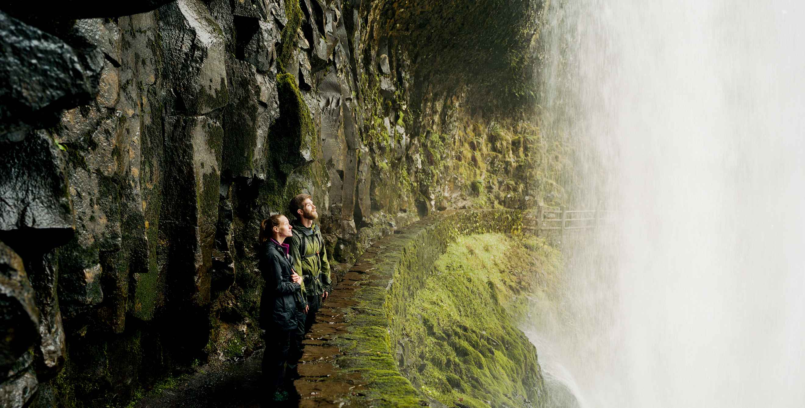 woman and man take in the view from behind a waterfall at Oregon's Silver Falls State Park, picture
