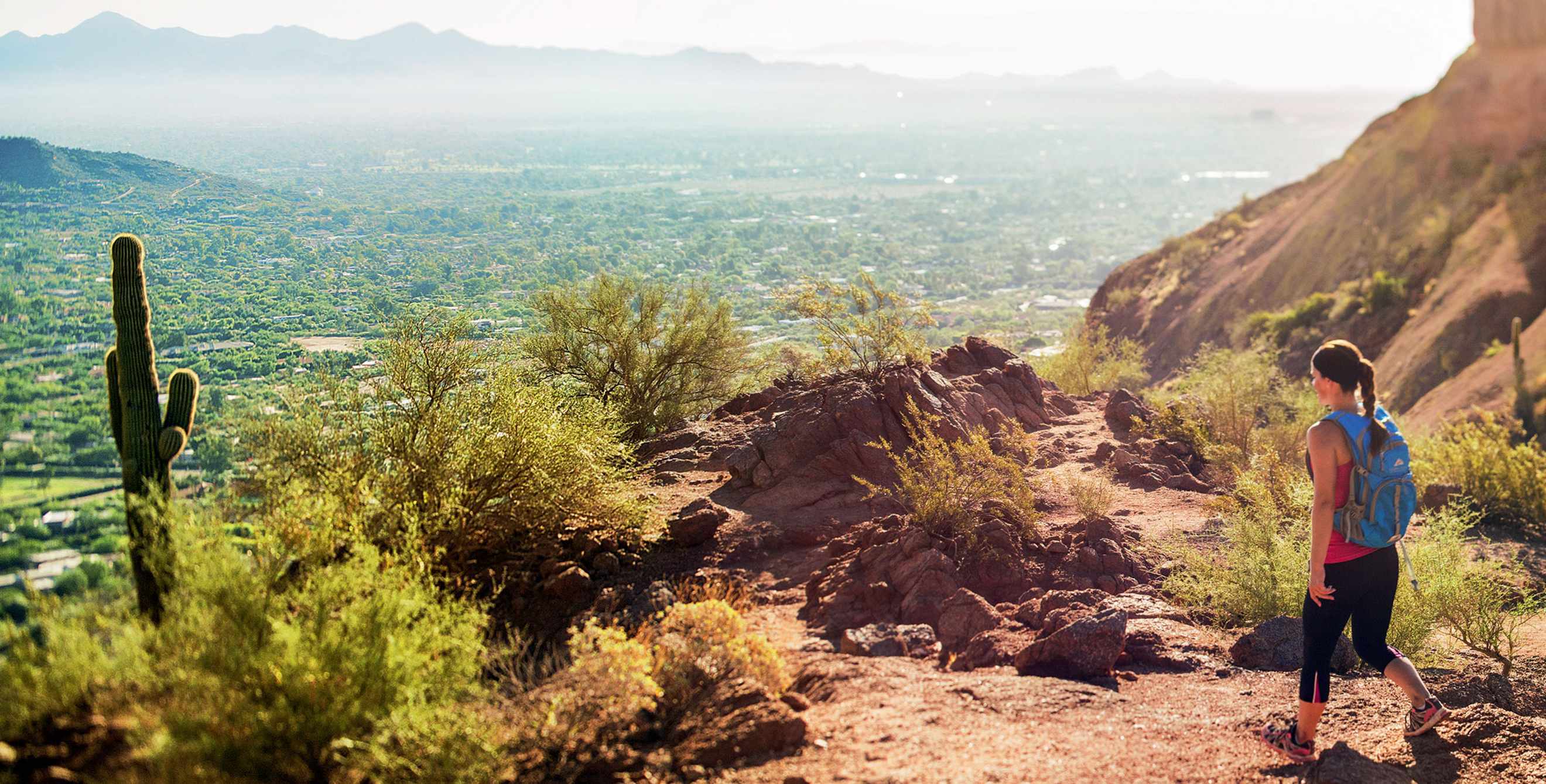 Woman hikes Echo Canyon Trail on Camelback Mountain in Phoenix, Arizona on a sunny day overlooking the city, picture