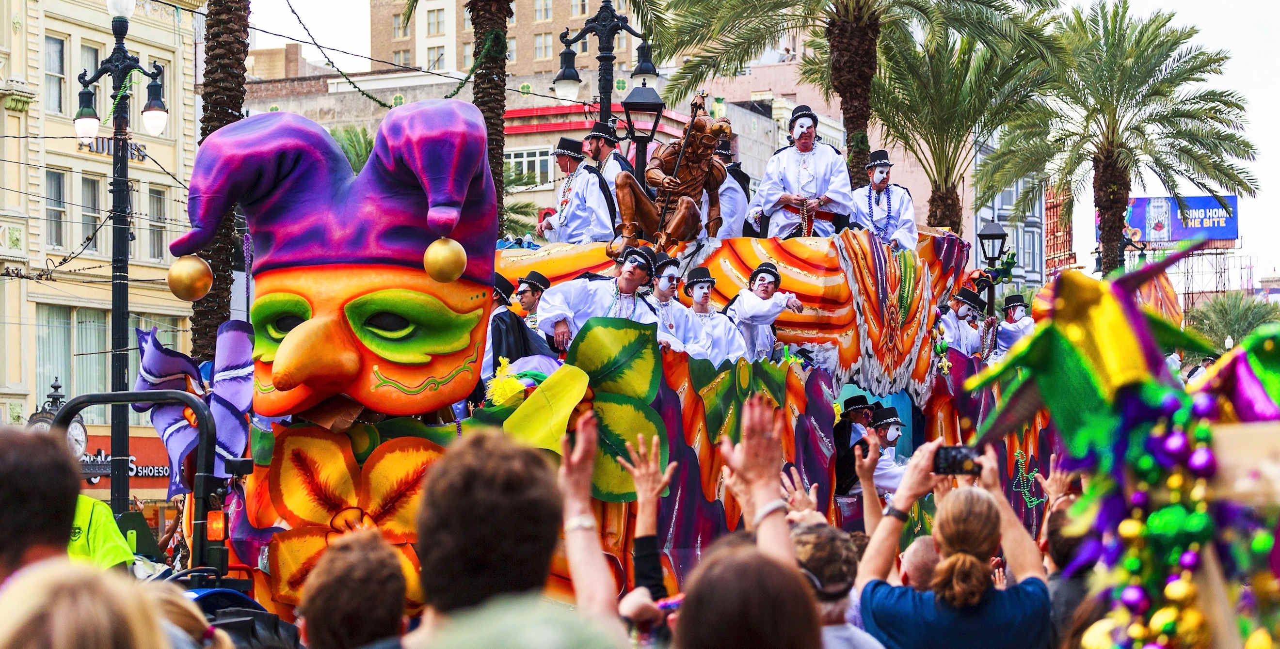 a float passes down a crowded street in New Orleans during the Mardi Gras parade