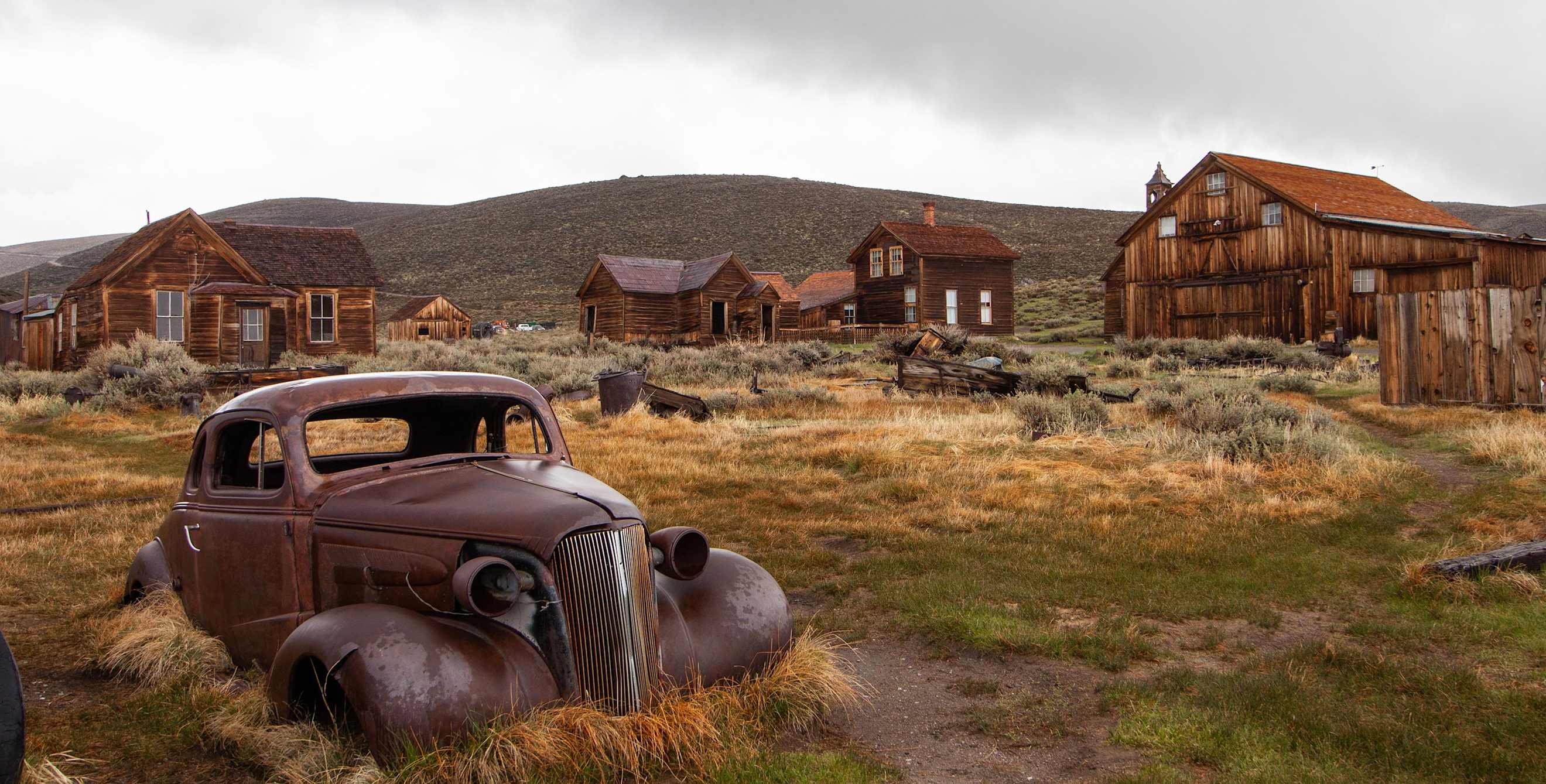 Rusted car and abandoned buildings in the ghost town of Bodie, California.