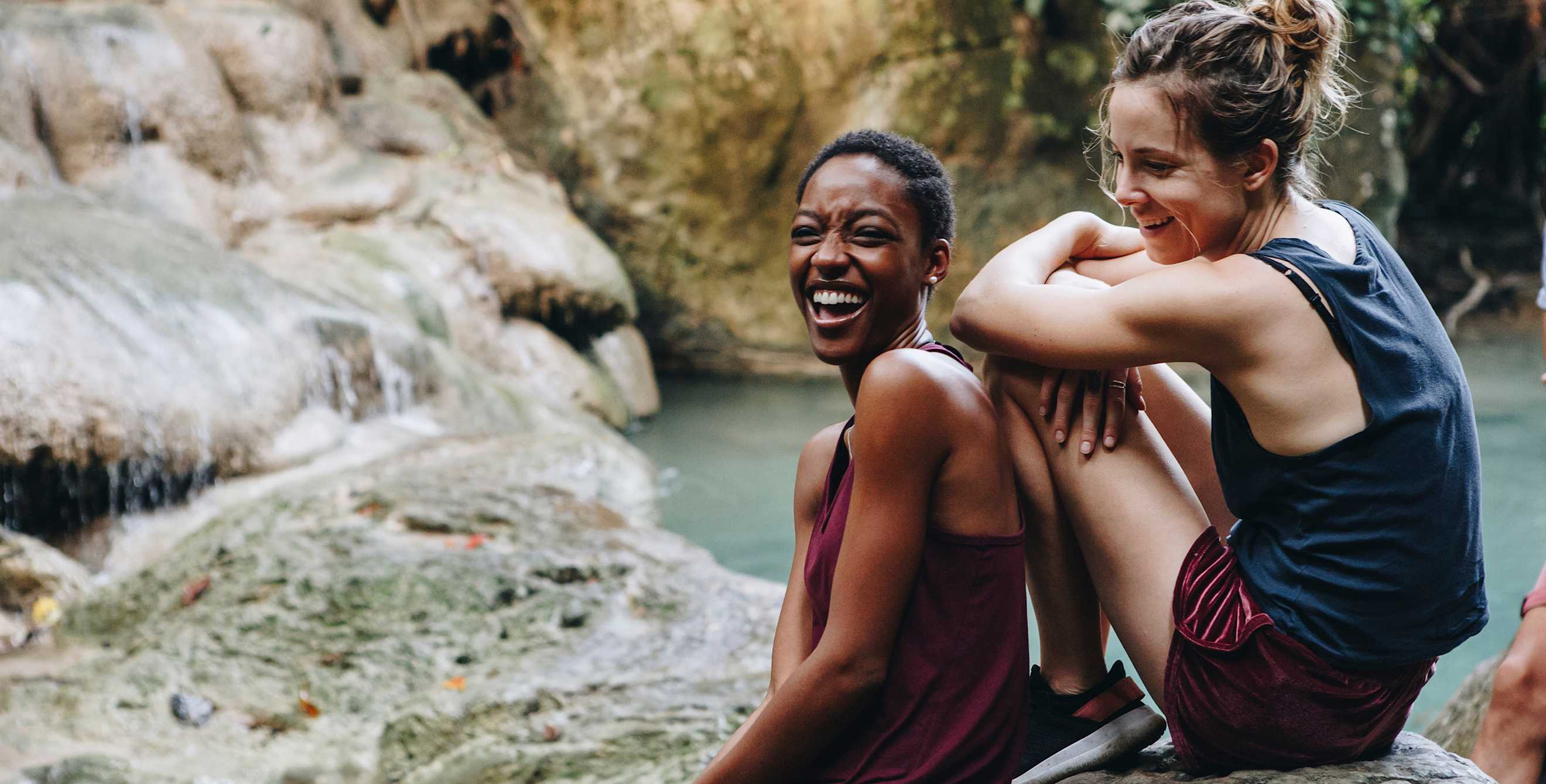 Two women laugh while resting on a hike, image