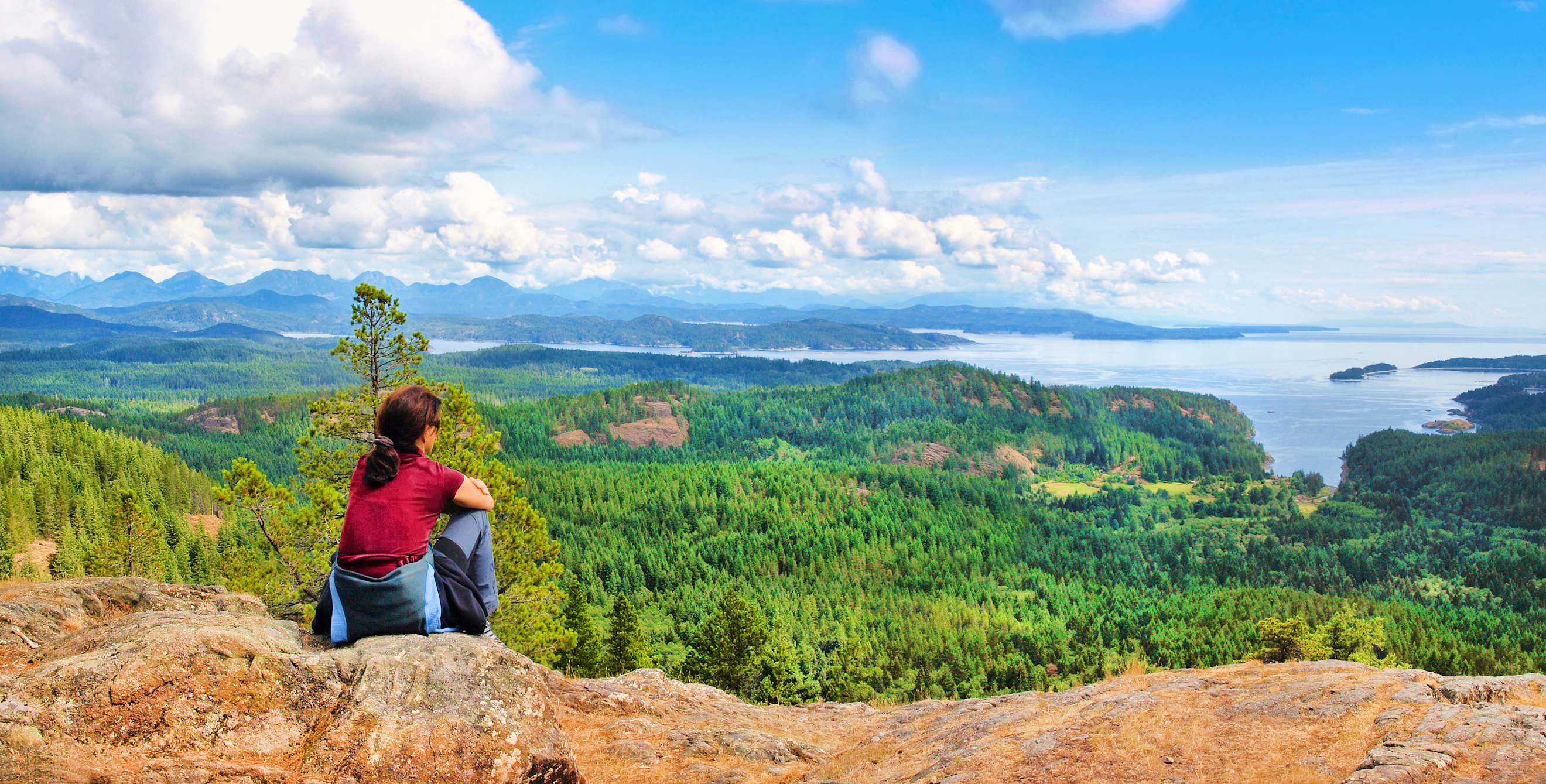 A woman sits on a mountain overlooking Vancouver Island in British Columbia