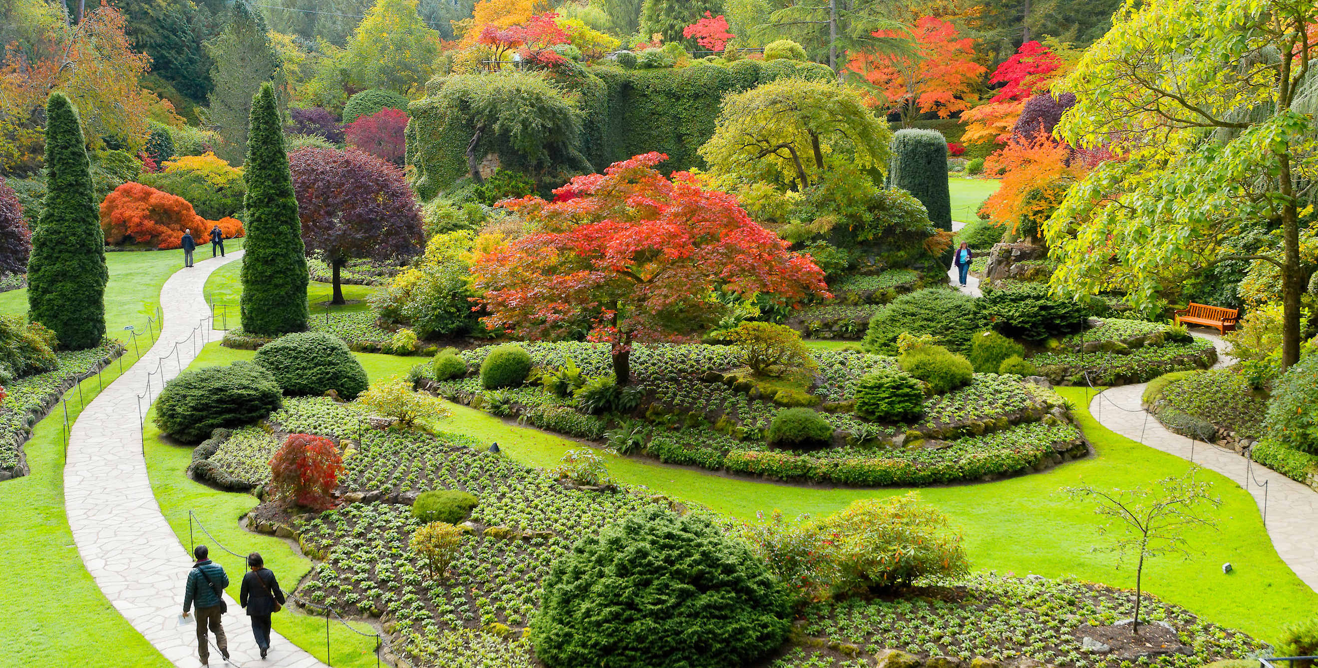 two people stroll the verdant Butchart Gardens in Victoria, B.C., picture