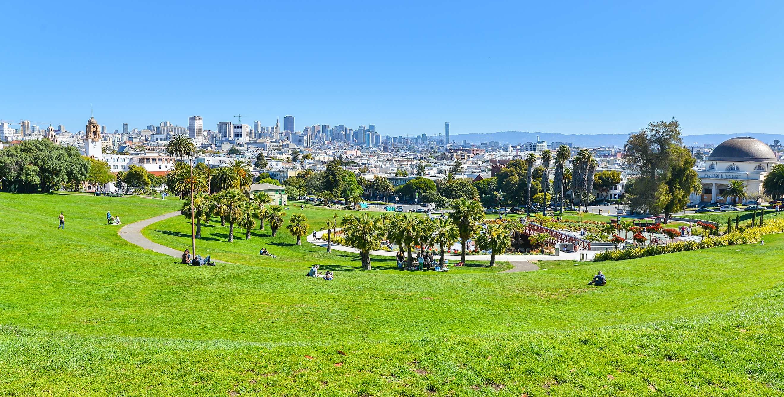 People relax in Mission Dolores Park on a sunny day, image