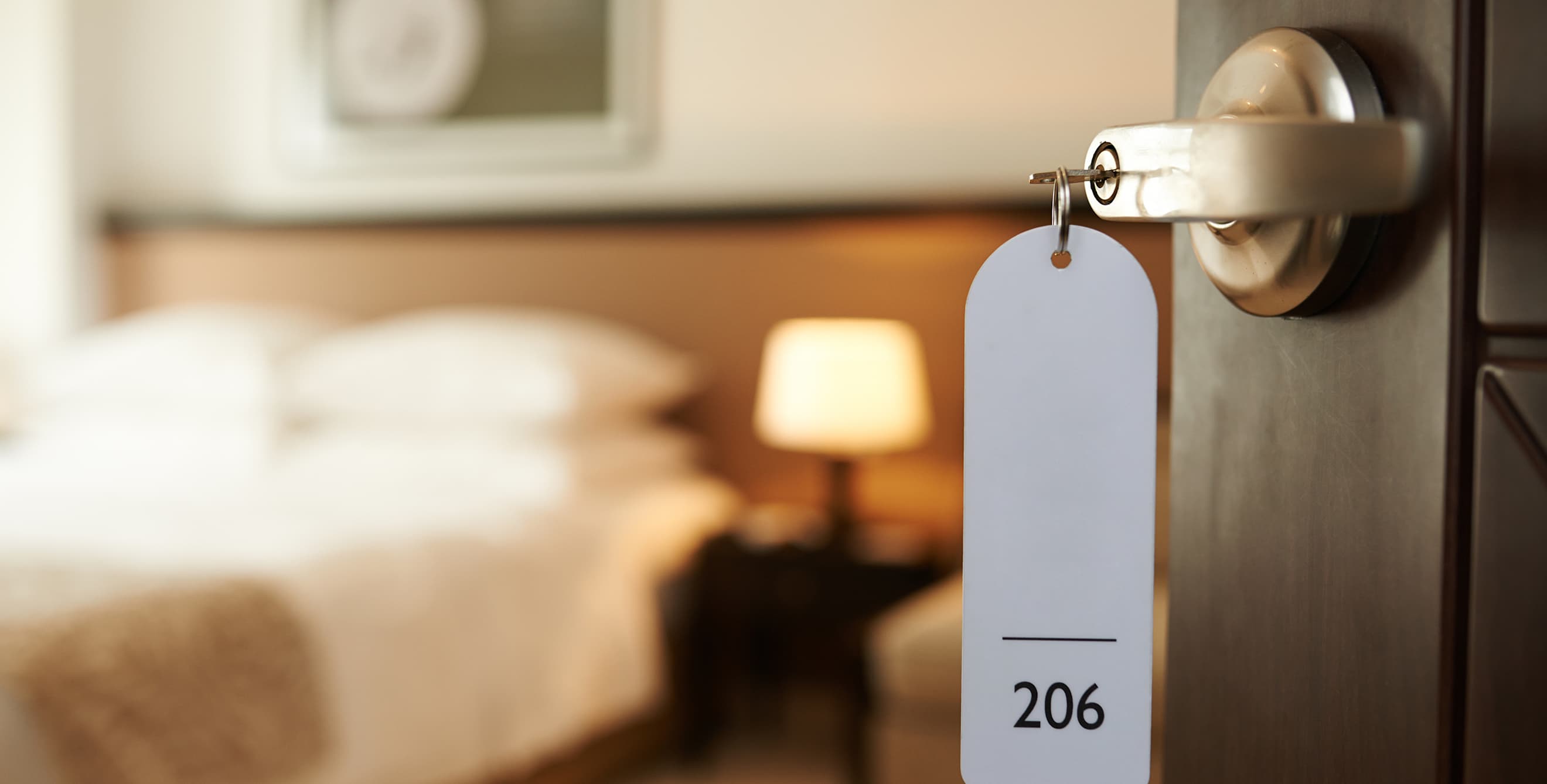 A room key hanging out of an open hotel room door, image