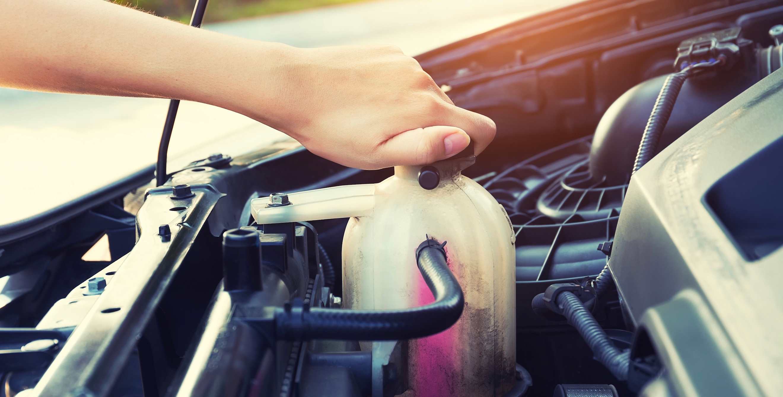 girl's hand checking level of coolant car engine