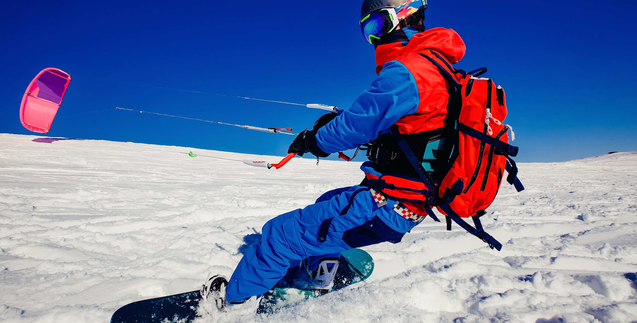 Snow kiter harnesses free wind energy on bright, cloudless day.