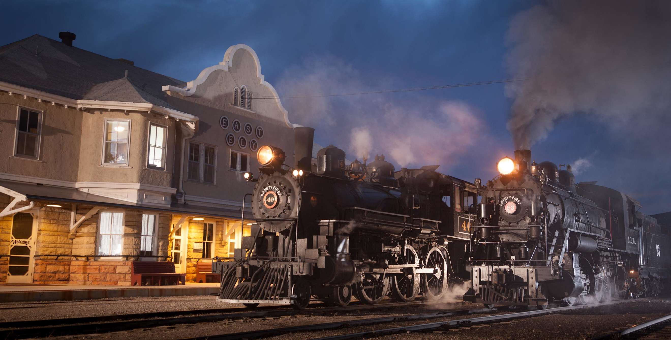 two steam train engines at the East Ely train depot at night, image
