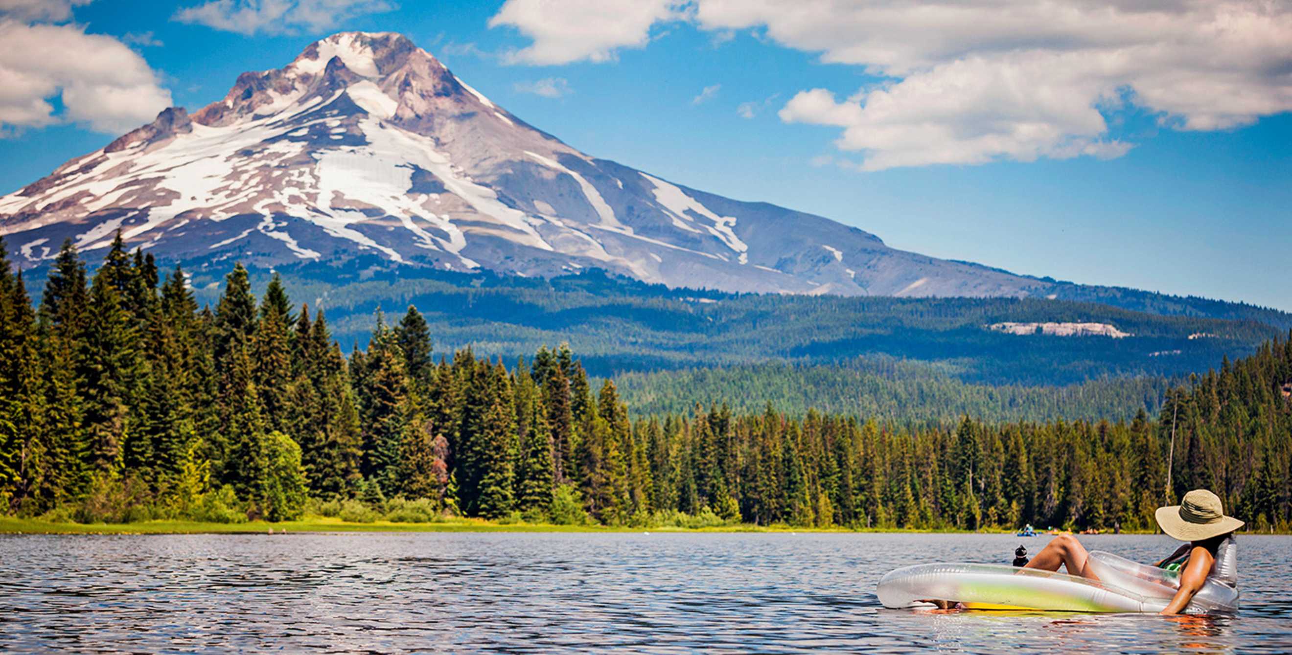 A woman floats on Trillium Lake in Oregon with Mount Hood in the background, picture