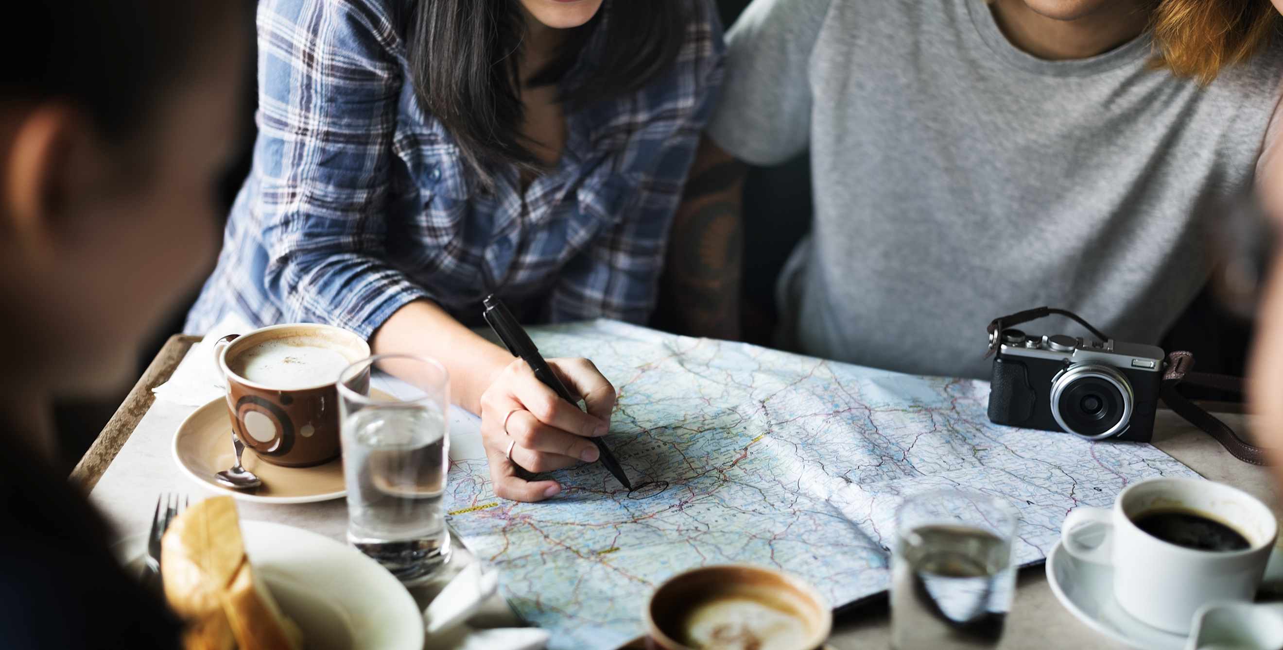 Friends gather around a map in a cafe, image