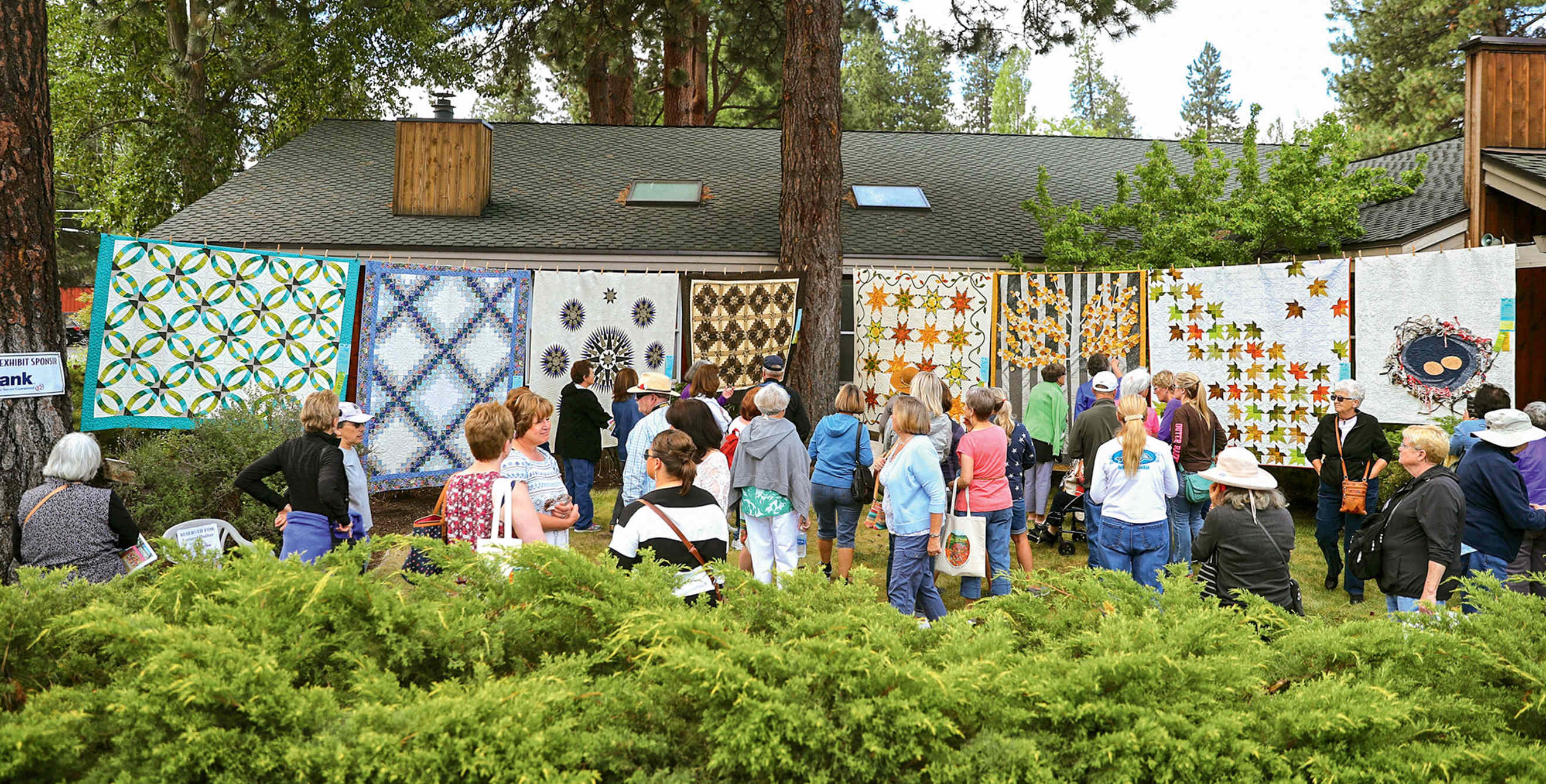 small crowd admires the custom quilts on display at Sisters Outdoor Quilt Show in Sisters, Oregon, picture