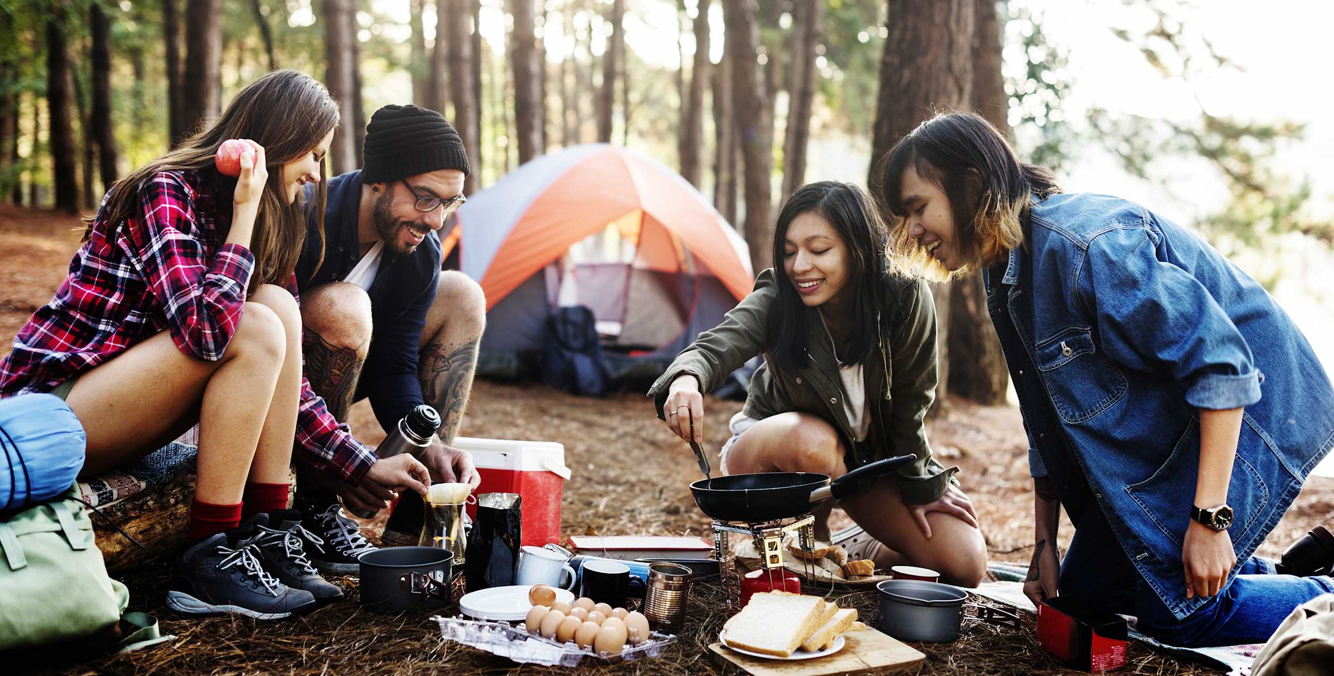 A group of friends cooking breakfast at their campsite with items off AAA's camping checklist