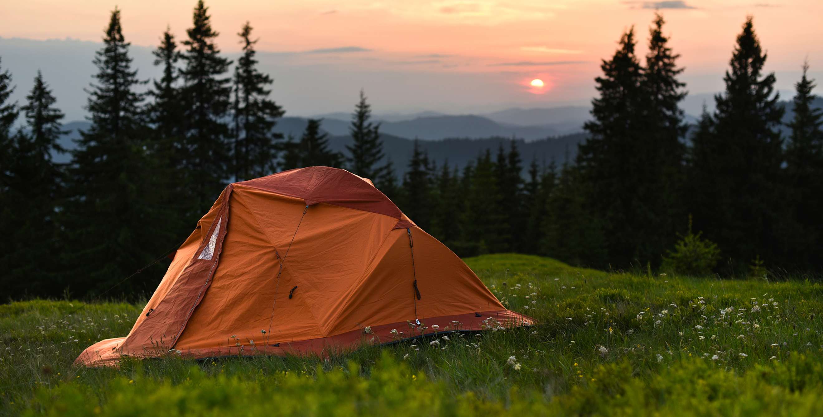 tent on a hill overlooking mountains at sunset, image