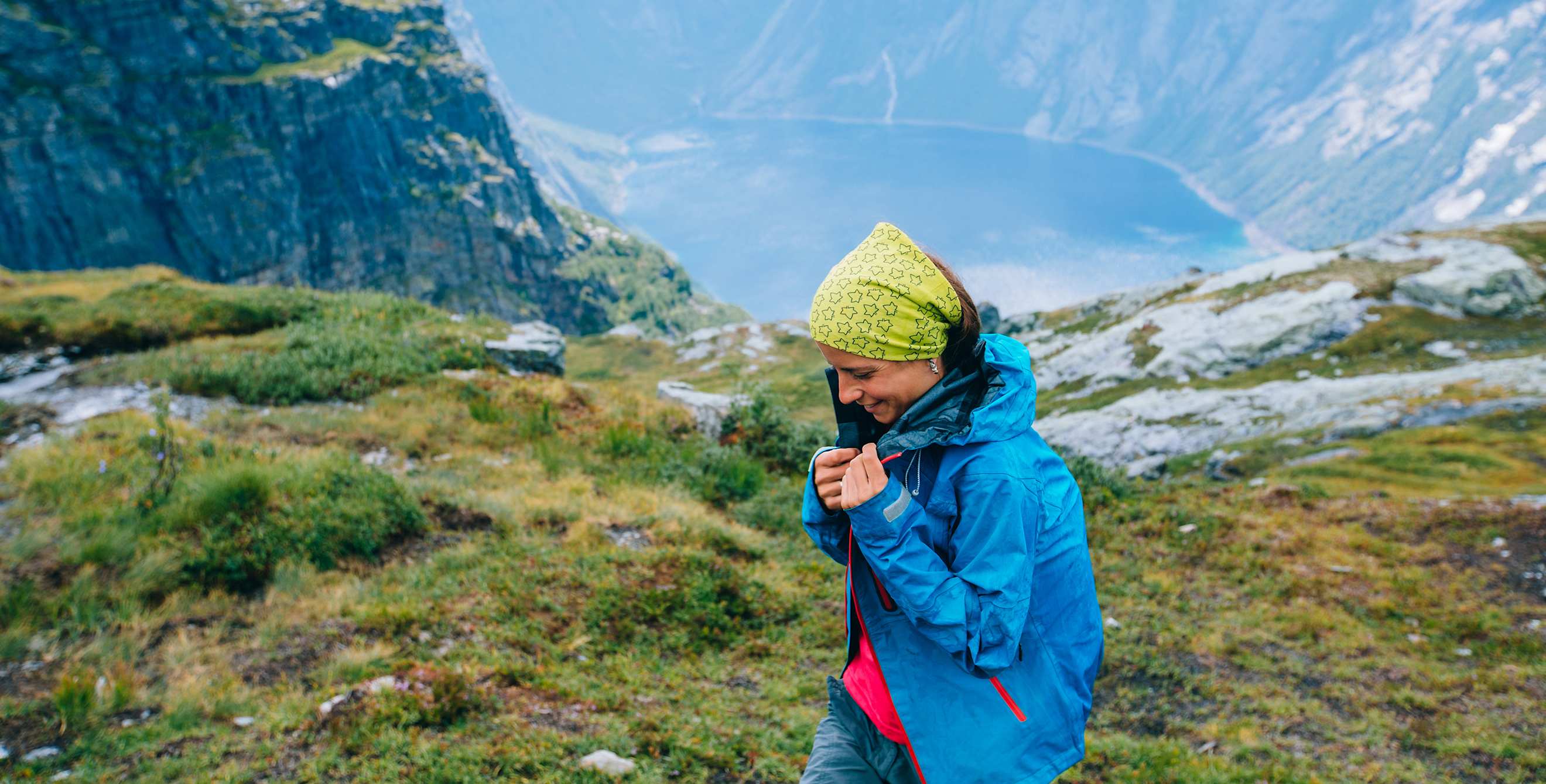 A hiker puts on a rain coat near a fjord in Norway.