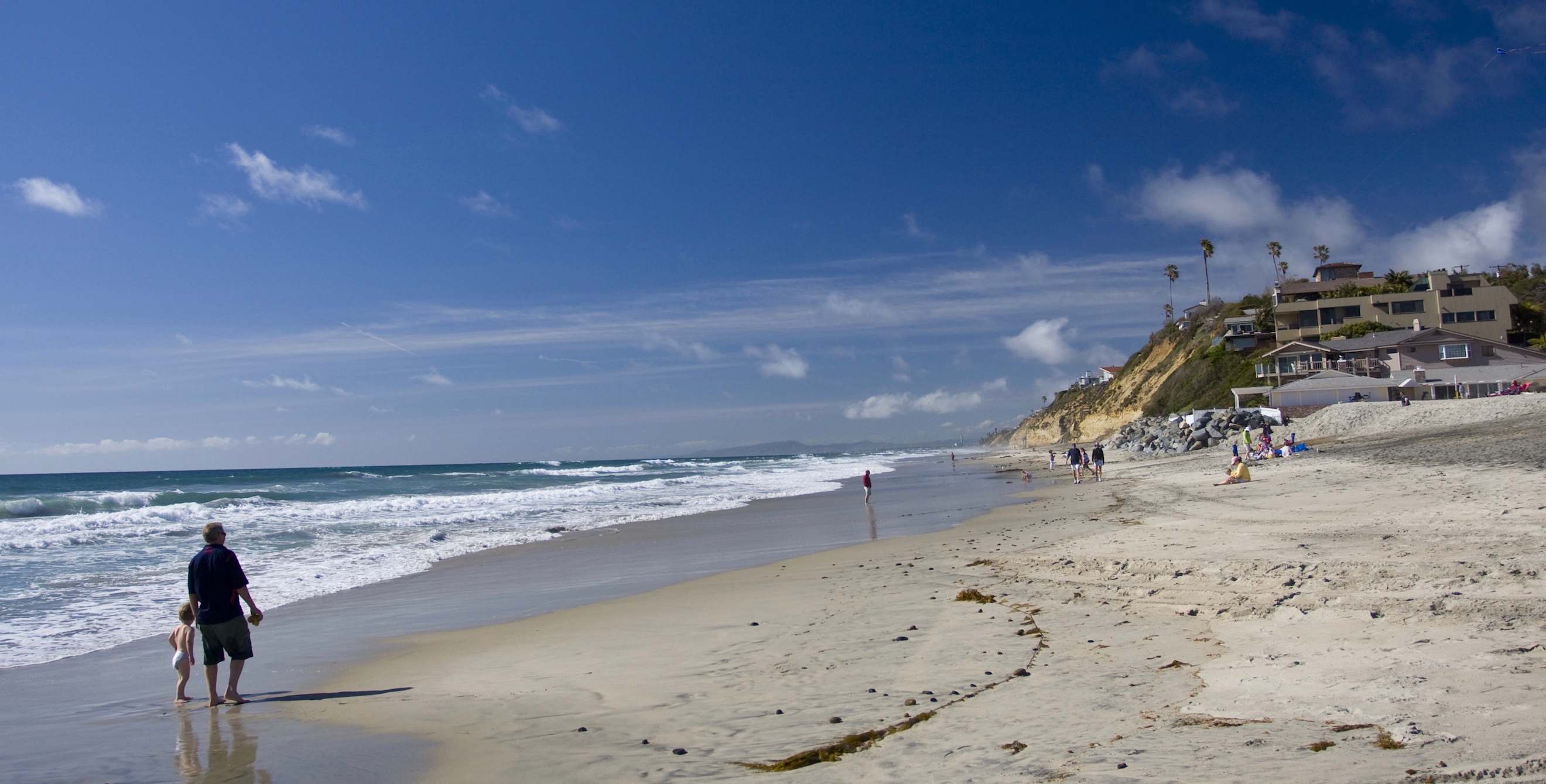 A father and daughter strolling the beach in Encinitas, California