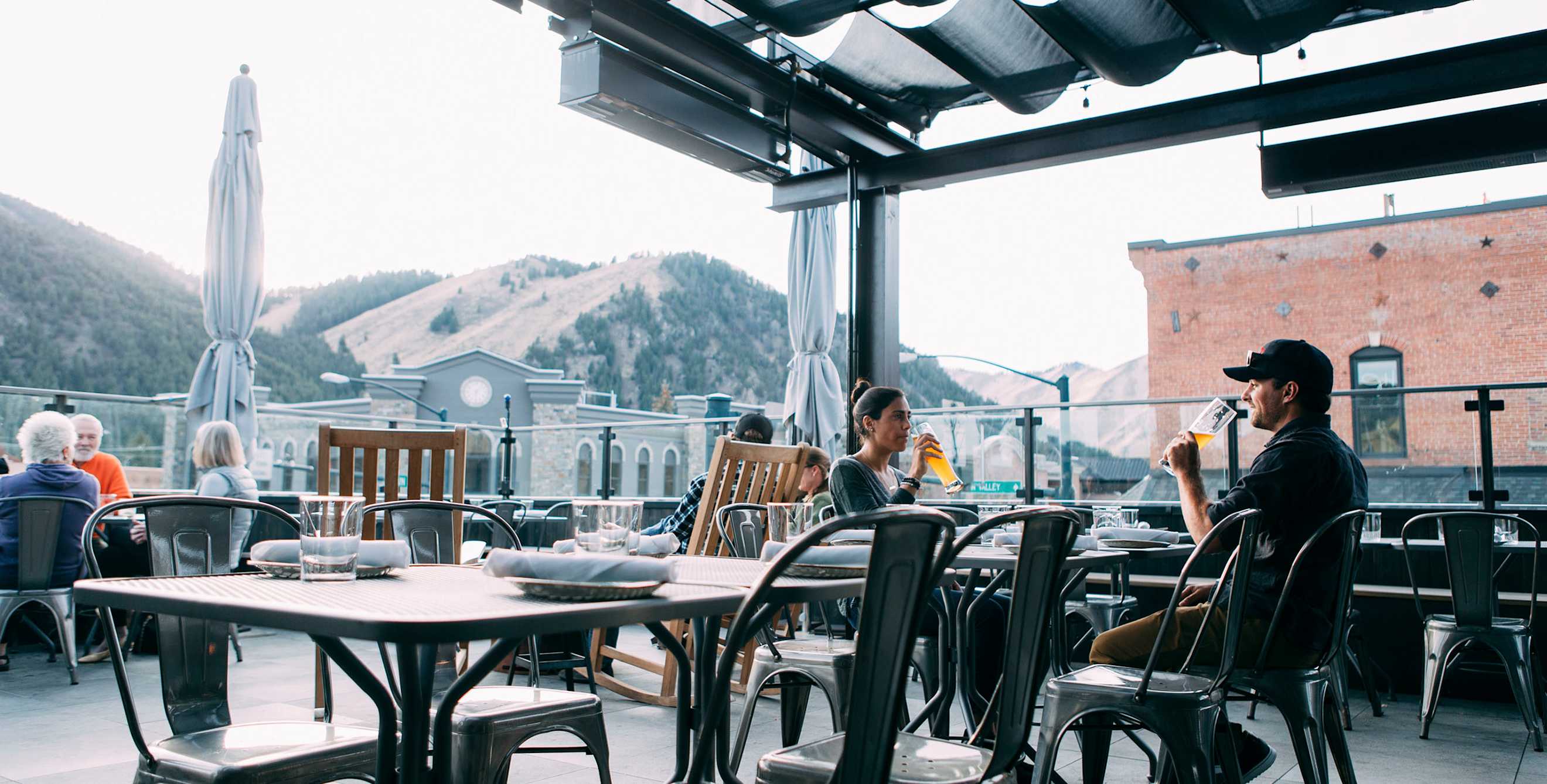 Warfield Distillery rooftop bar guests sip drinks beneath the covered seating area in downtown Ketchum, Idaho