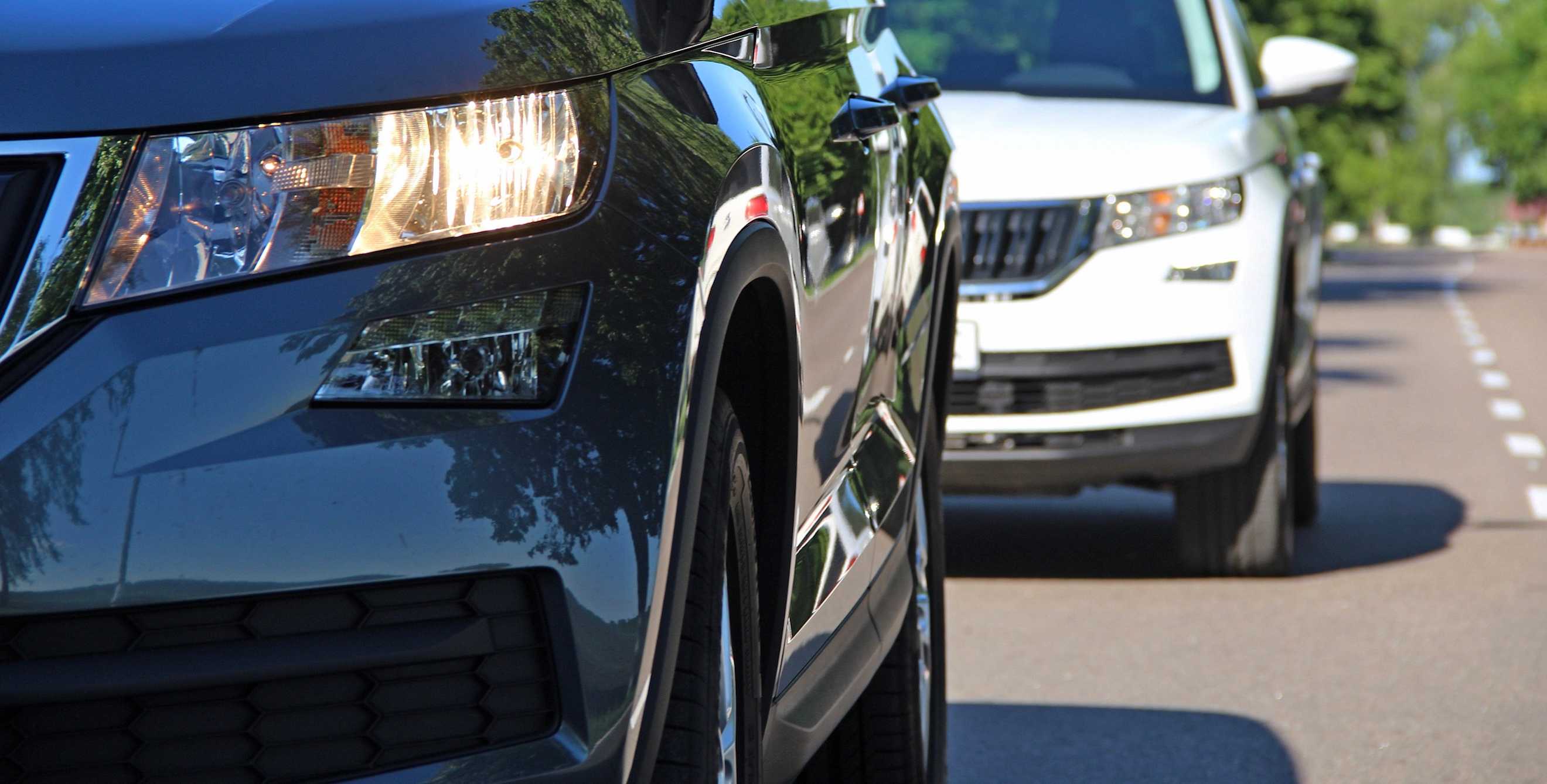 a close-up of two cars driving on a suburban road