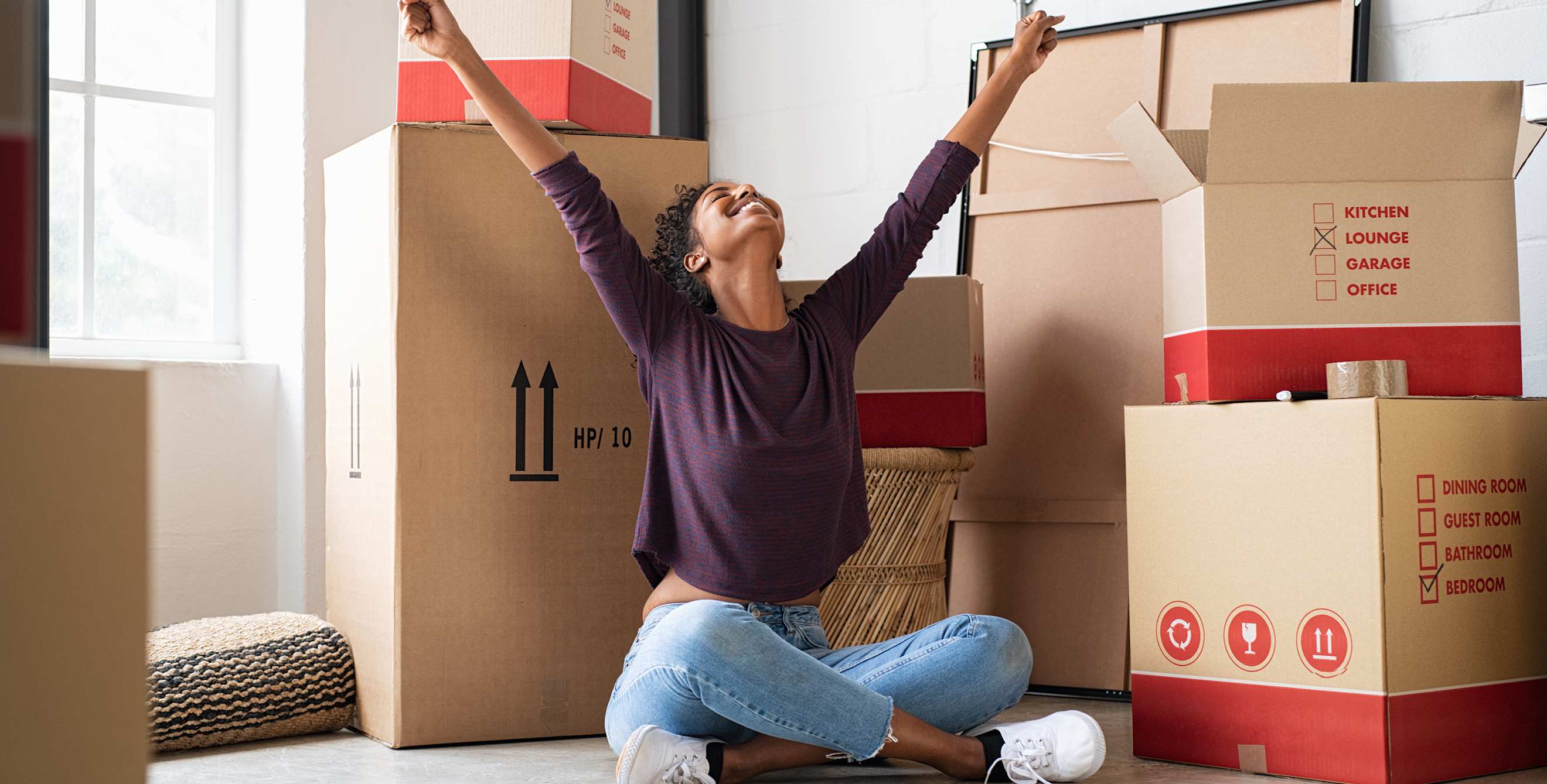A woman sits in front of boxes in her new apartment.