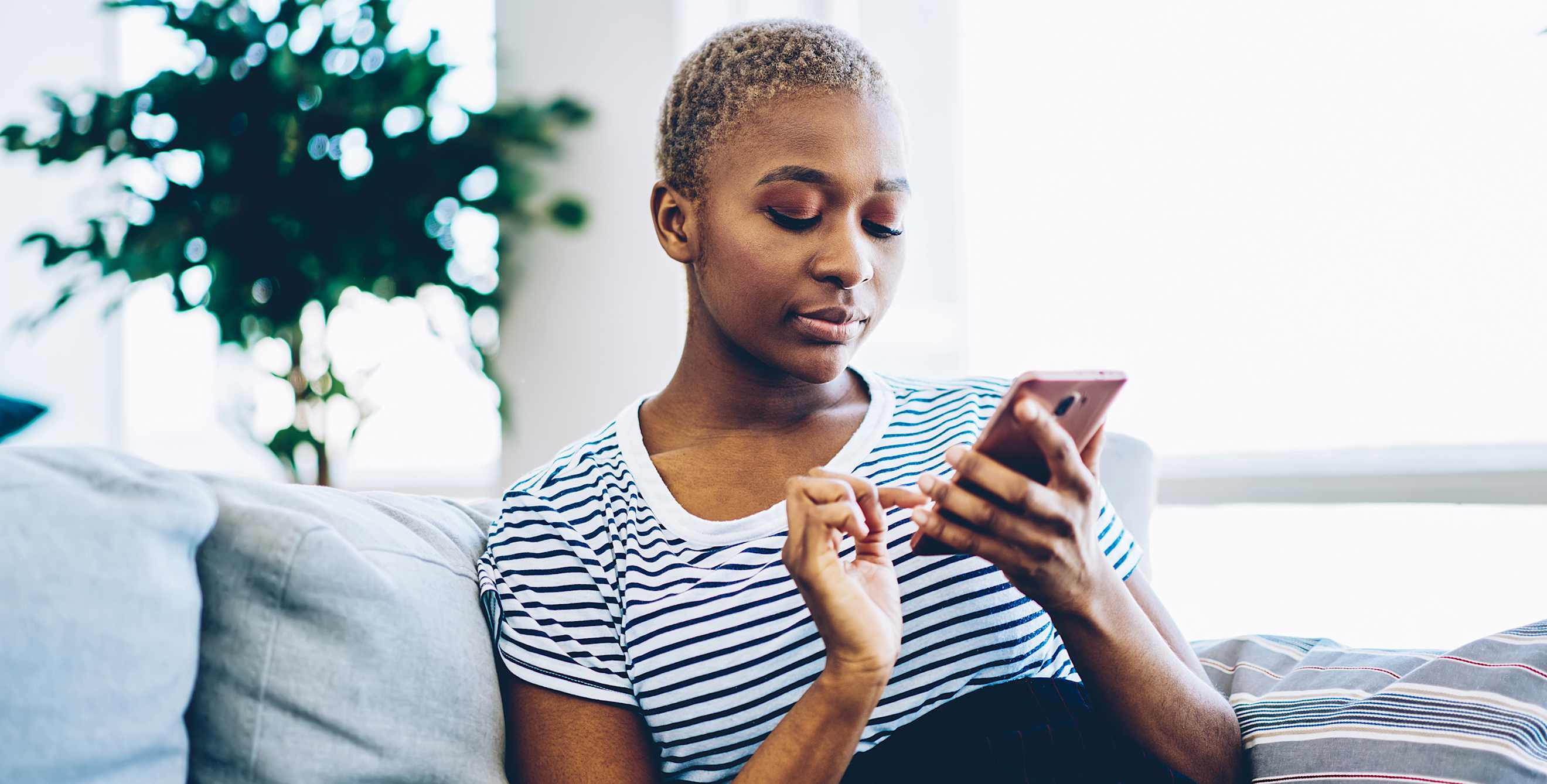 A woman uses her cell phone on the couch.
