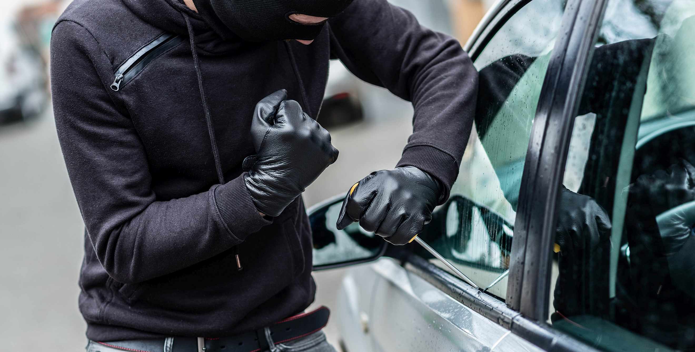A person breaks into a parked car.
