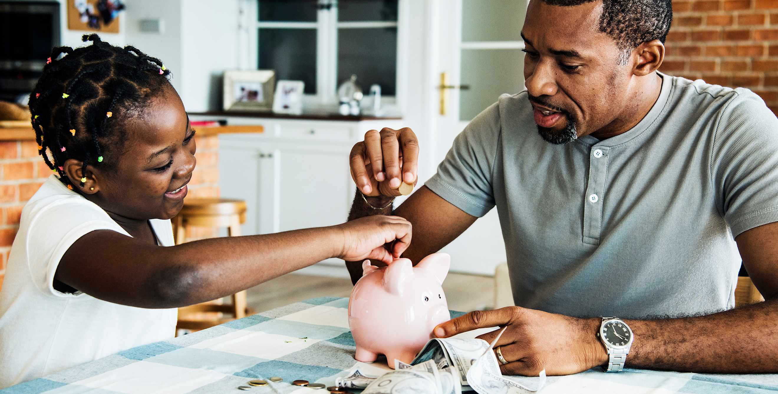 Father and daughter put change into a piggy bank.