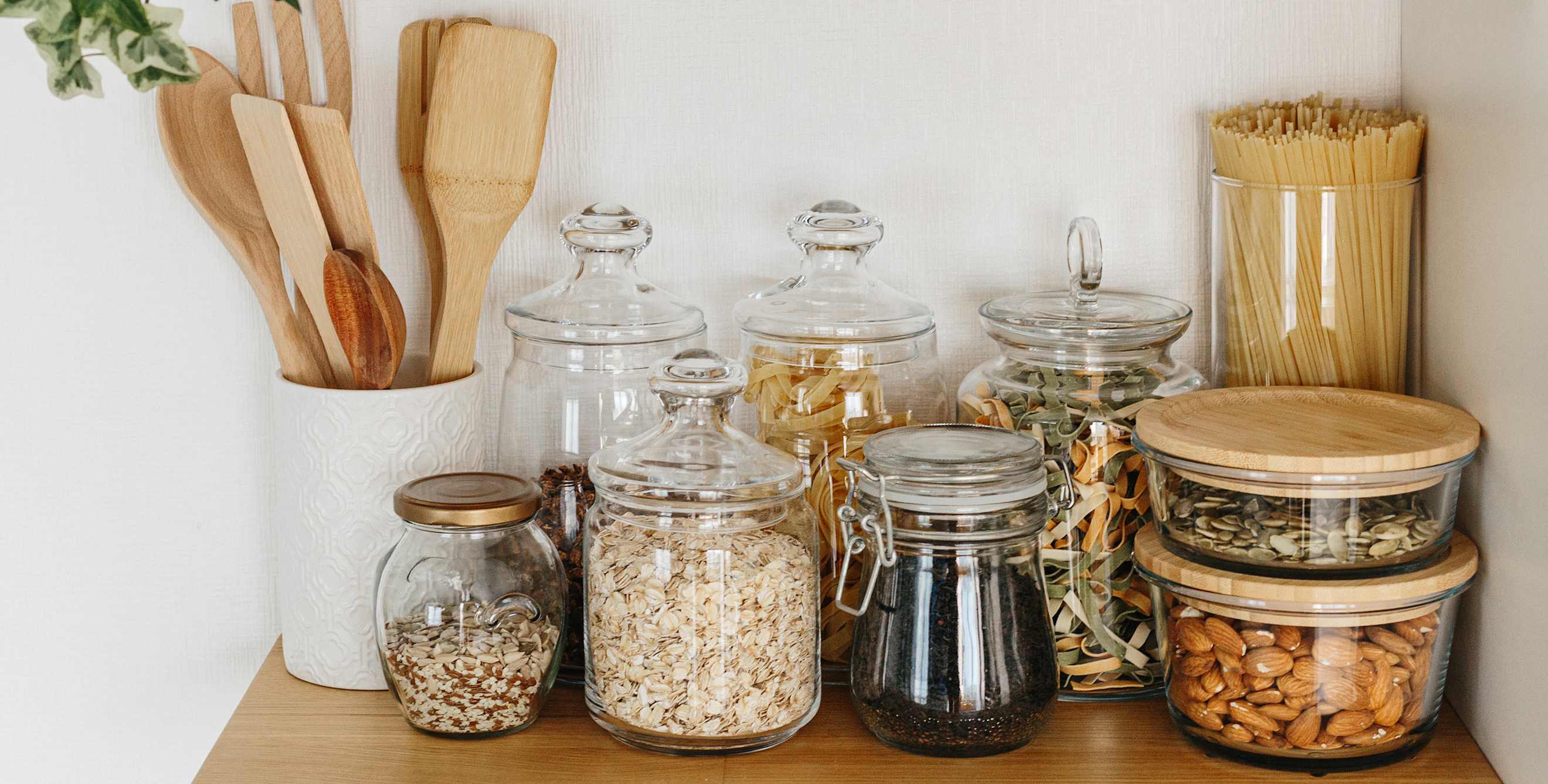 Glass jars with pantry staples on an open shelf.