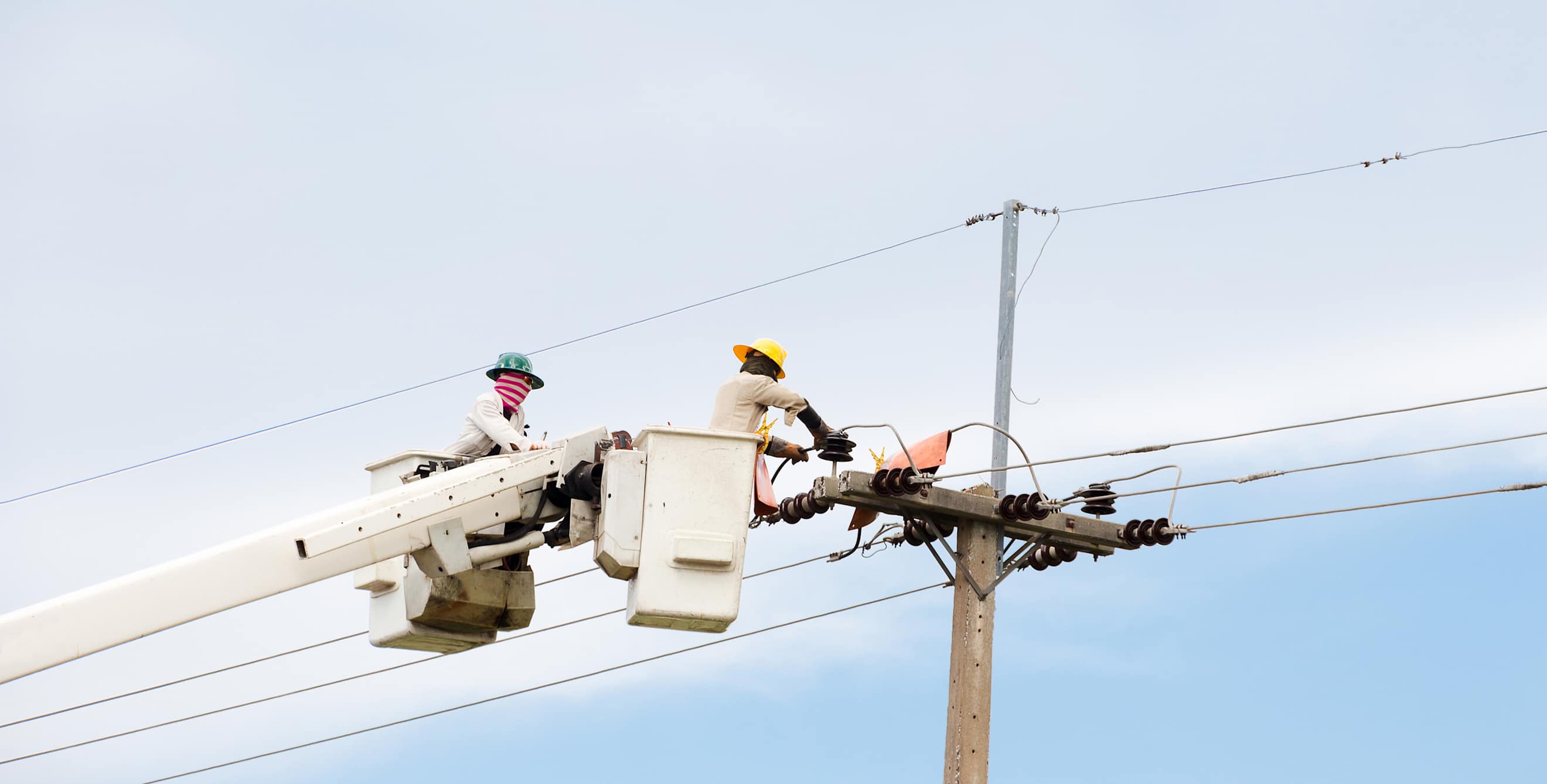 Two repair people work on a power line.