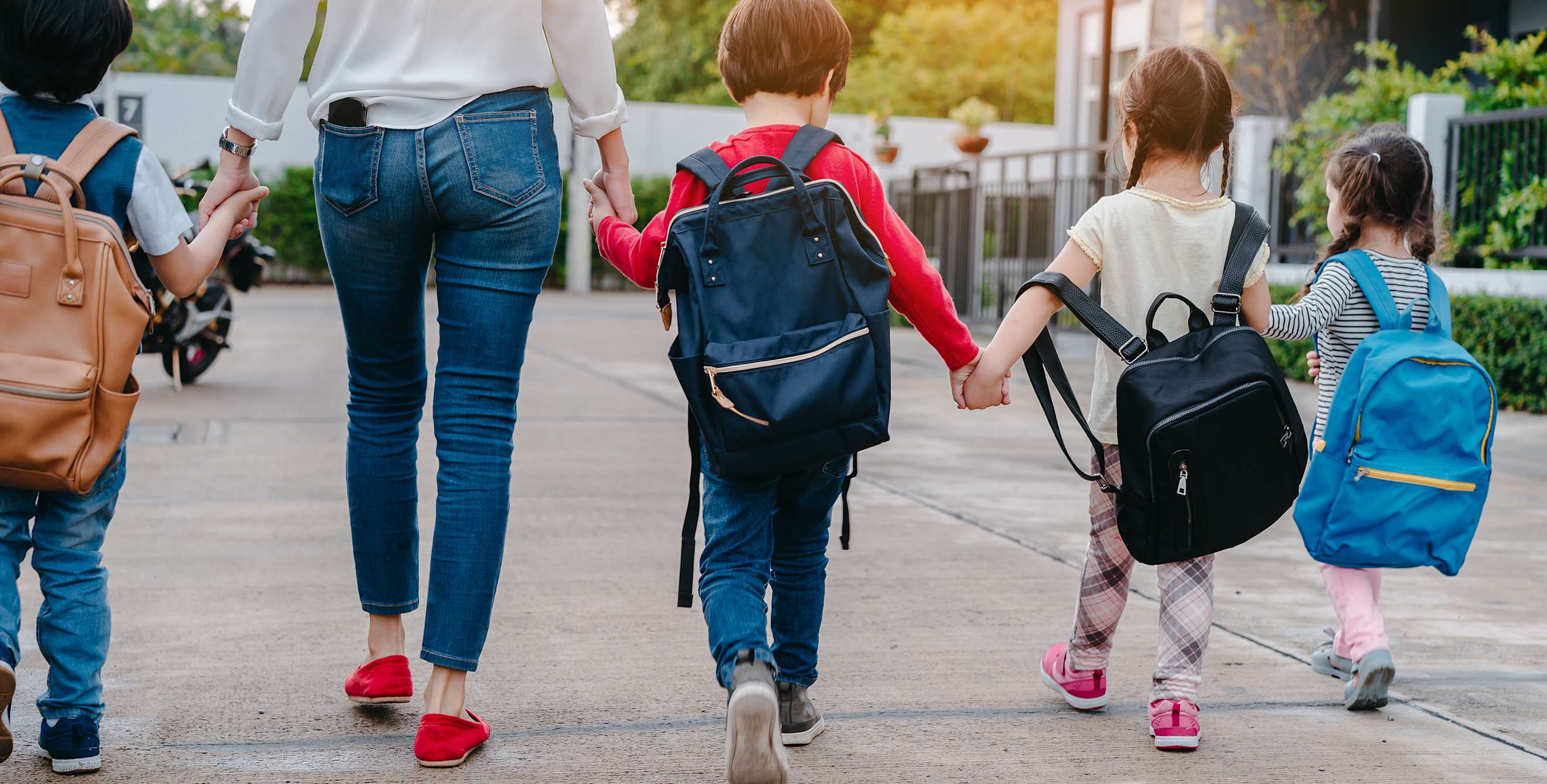 A mom walks young kids to school.