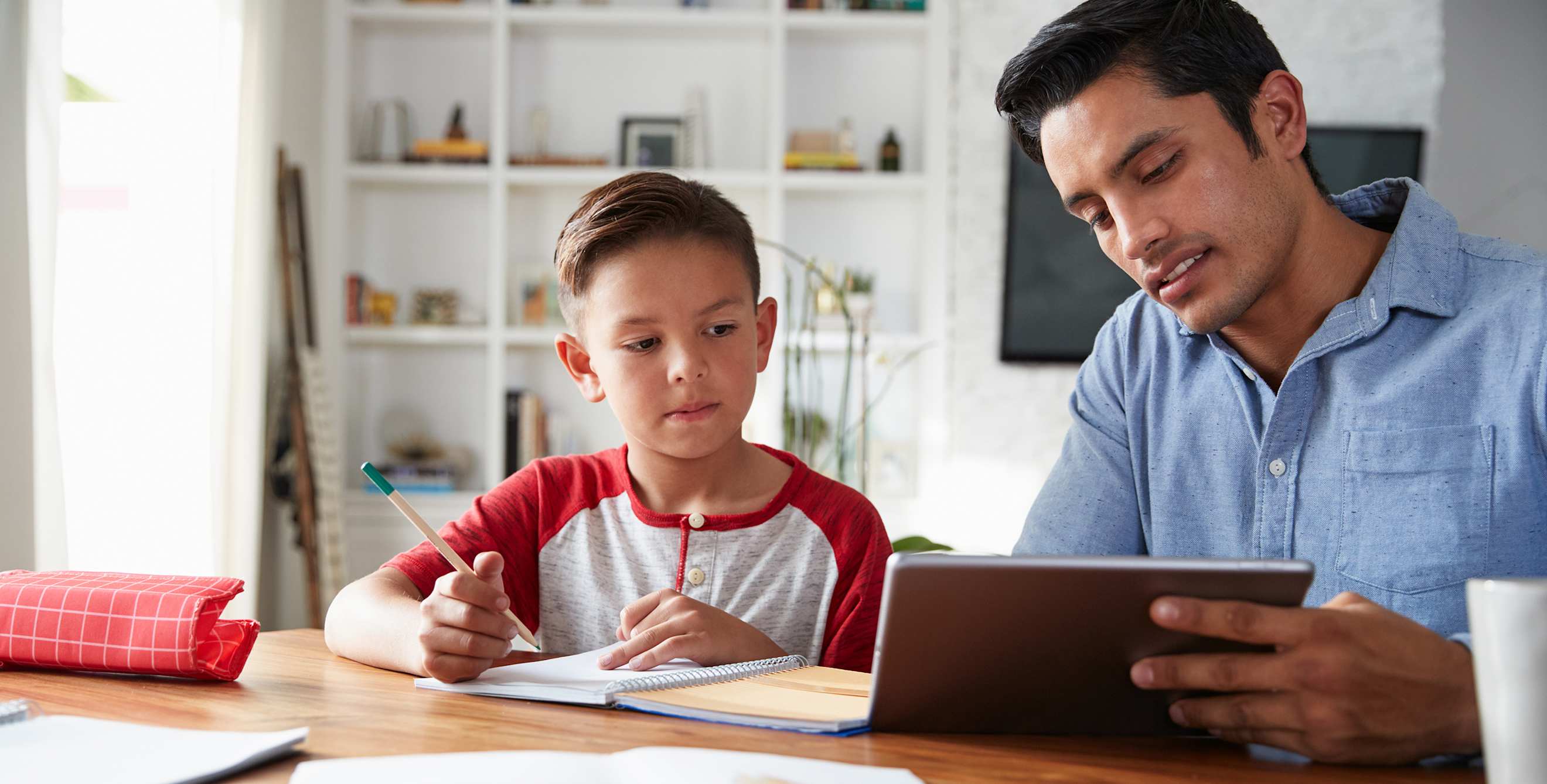 A dad uses a tablet to teach his son.