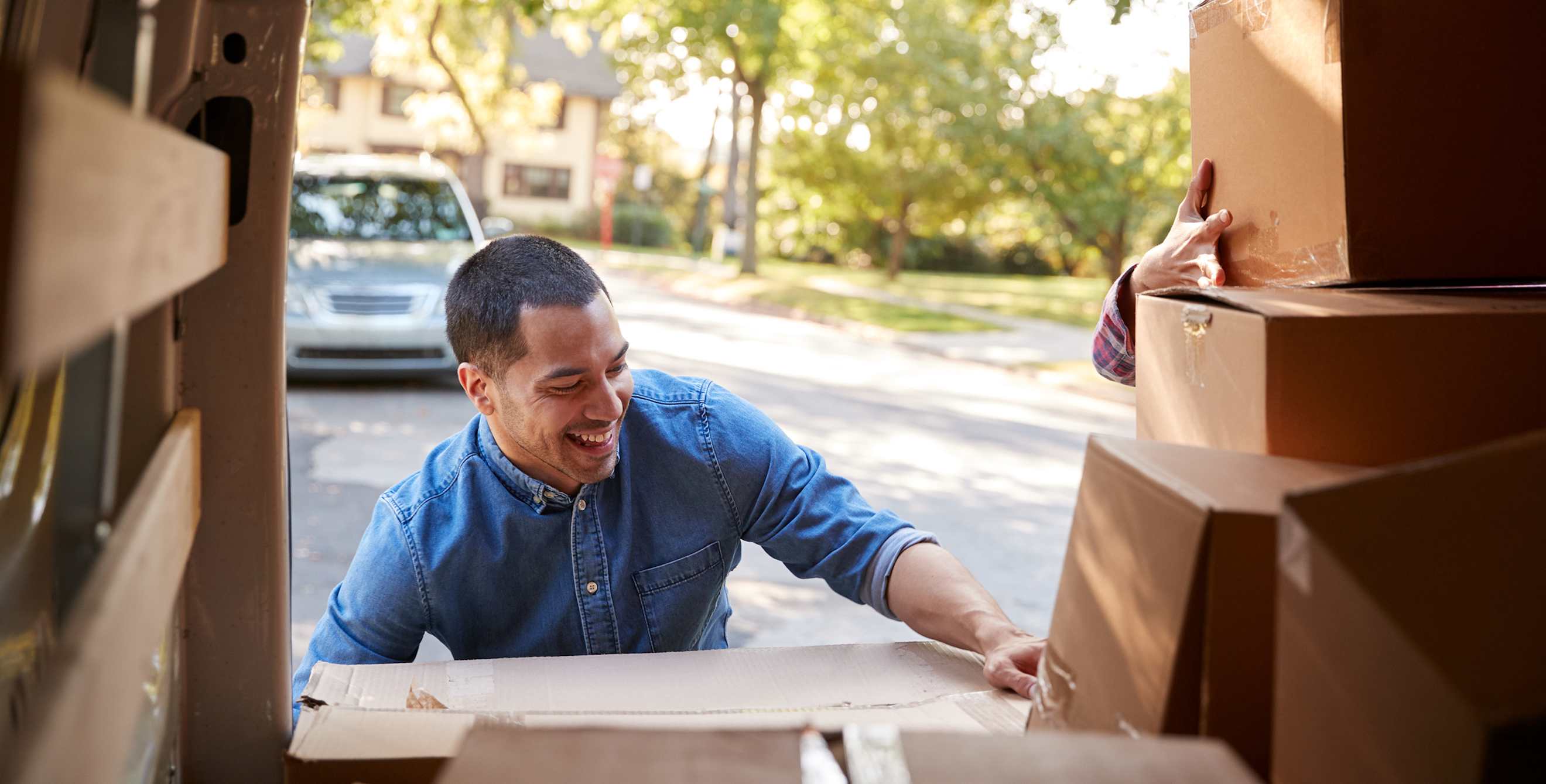 A man picks up a box out of the back of a moving truck.